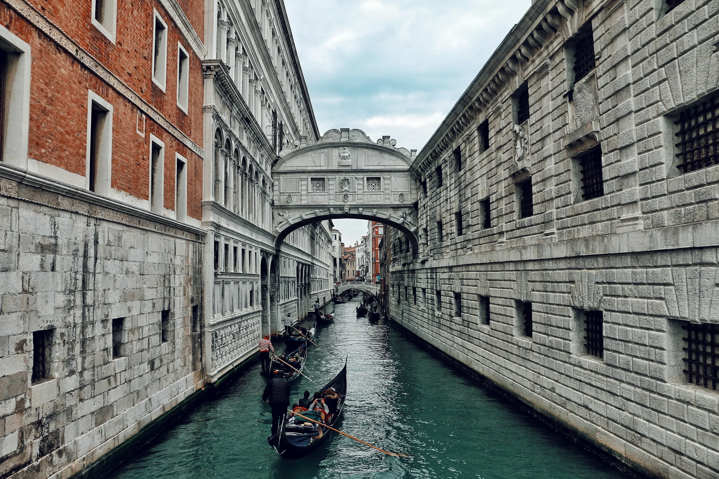 Bridge of Sighs di Venice dengan gondola di kanal di bawah langit pucat.