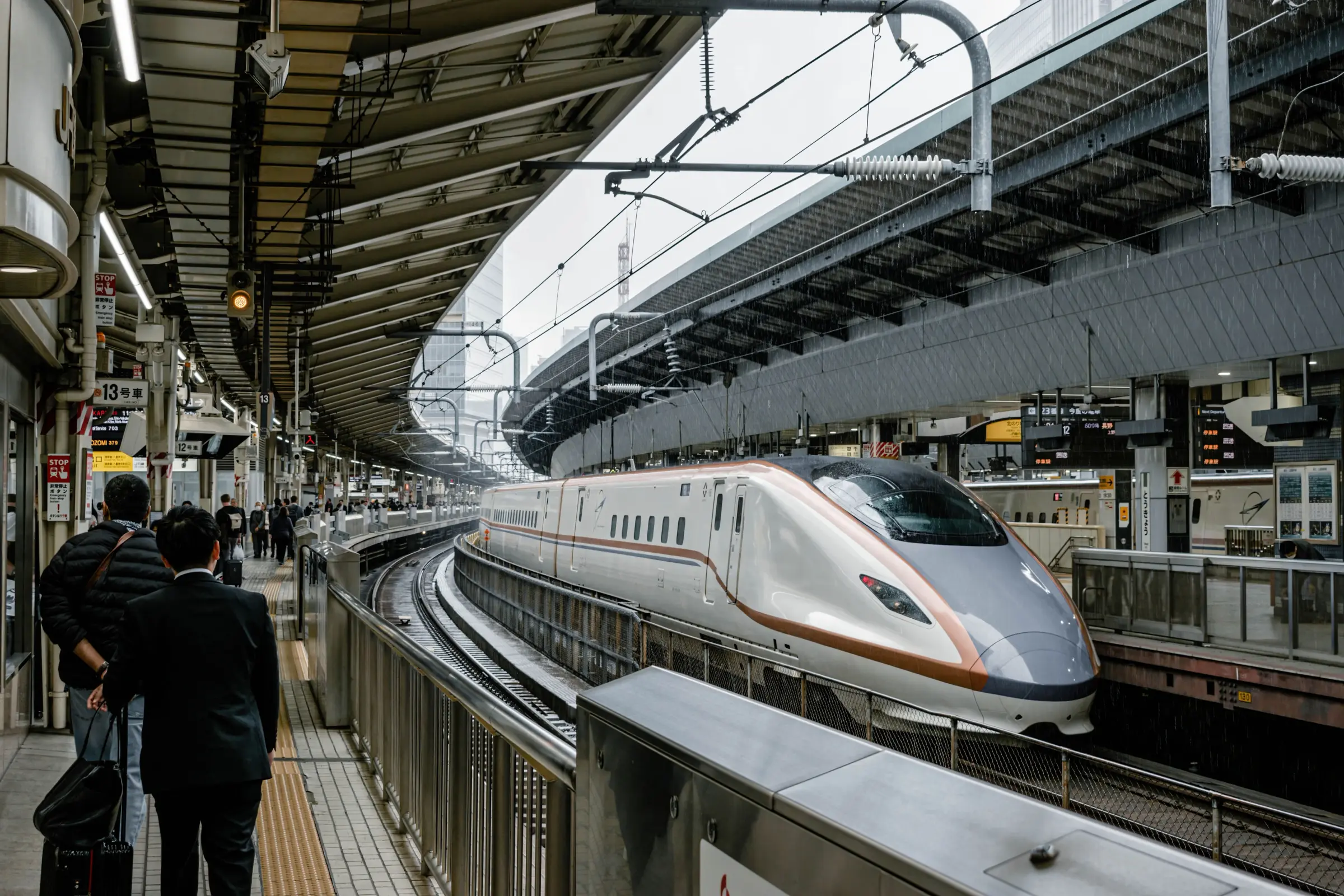 Kereta Shinkansen melengkung memasuki peron stasiun Jepang dengan penumpang menunggu