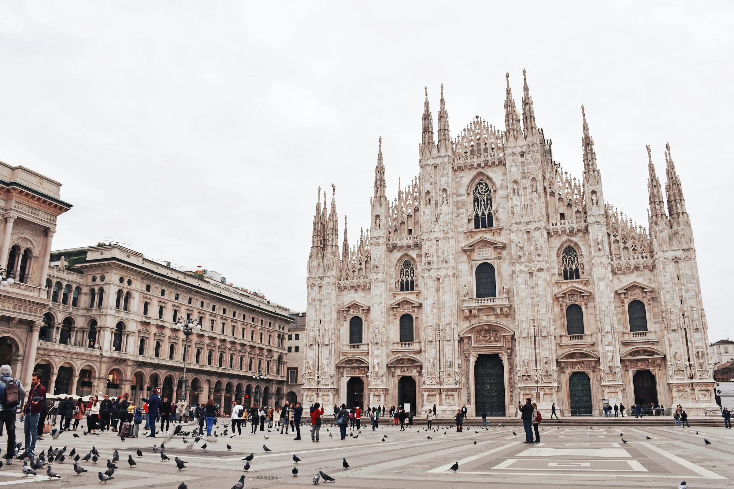 Duomo di Milano di Piazza del Duomo dengan merpati dan langit putih pucat.