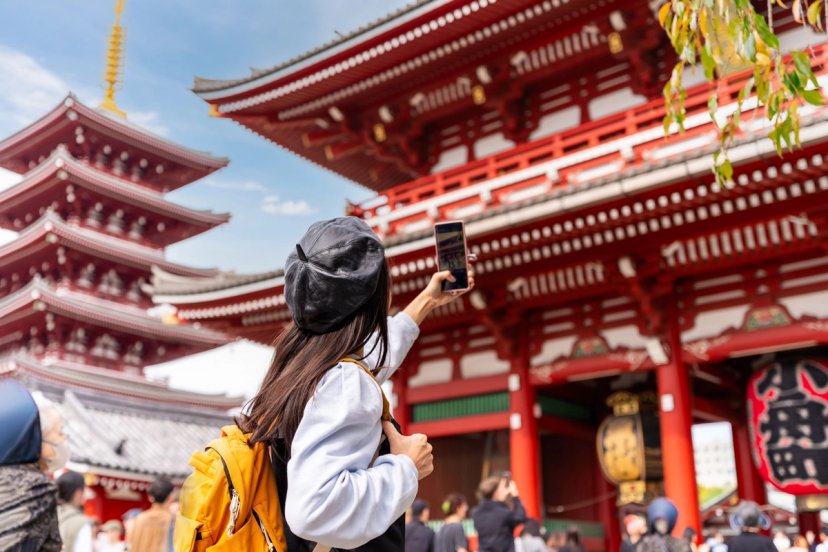 Perempuan berjas putih dan syal merah di Nakamise-dori dengan gerbang Hozomon Sensoji di belakang, Asakusa Tokyo