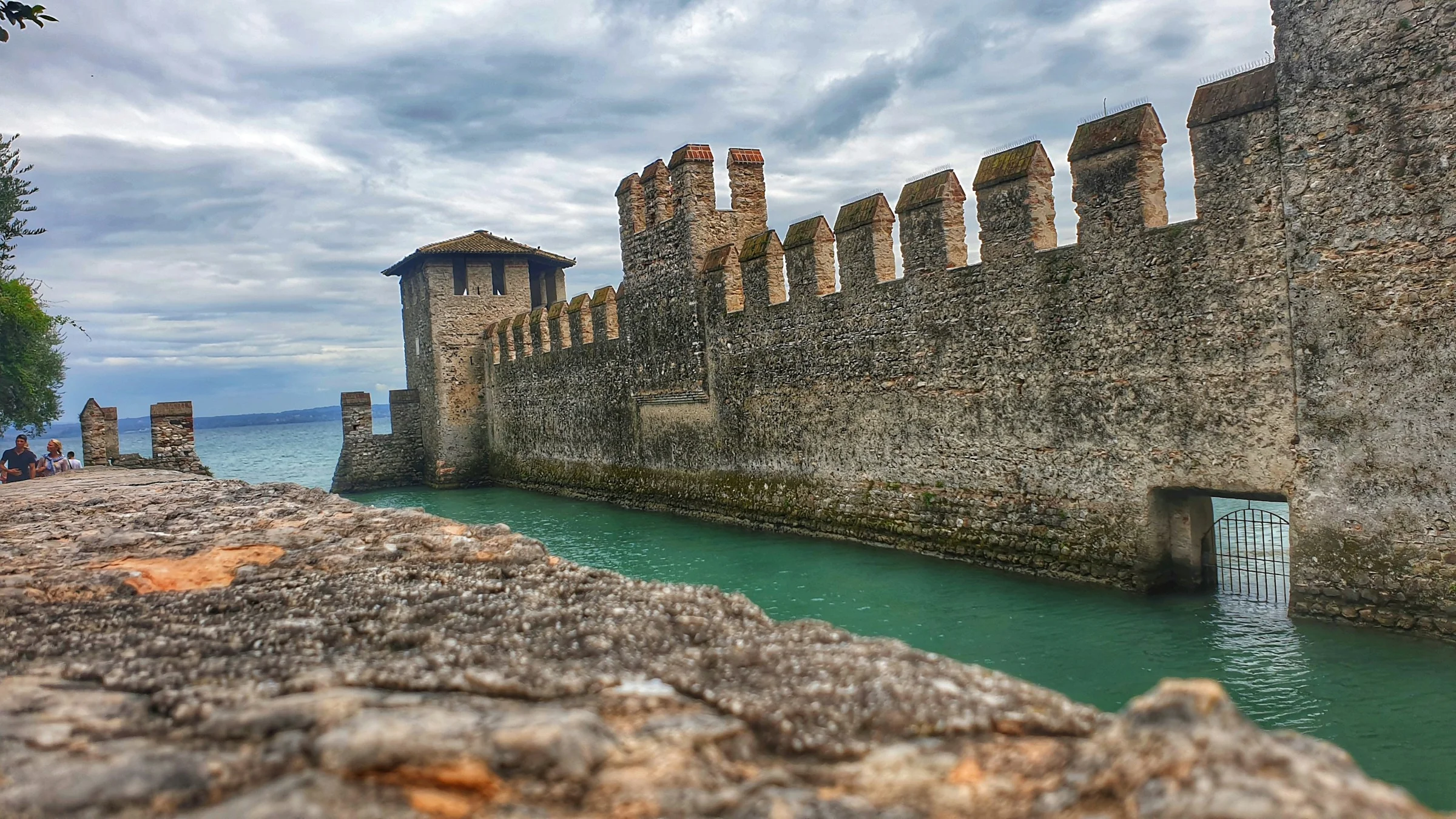 Tembok dan menara kastil Sirmione di tepi Danau Garda yang berwarna toska.
