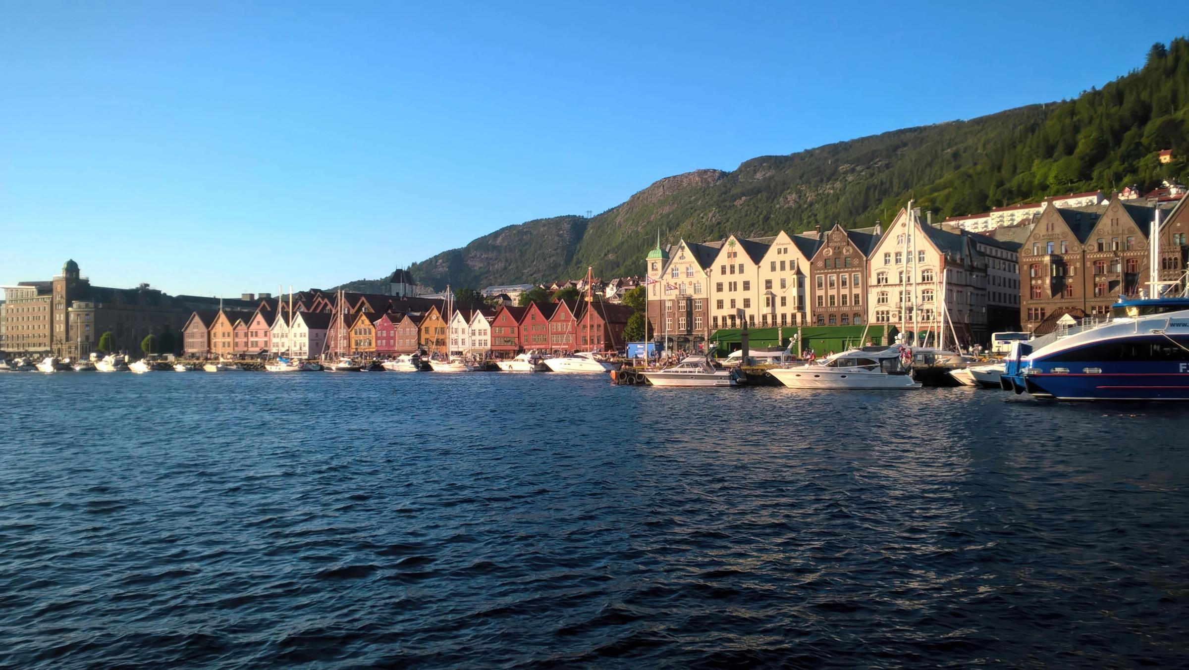 Deretan rumah kayu warna-warni Bryggen Bergen di tepi pelabuhan dengan langit biru cerah