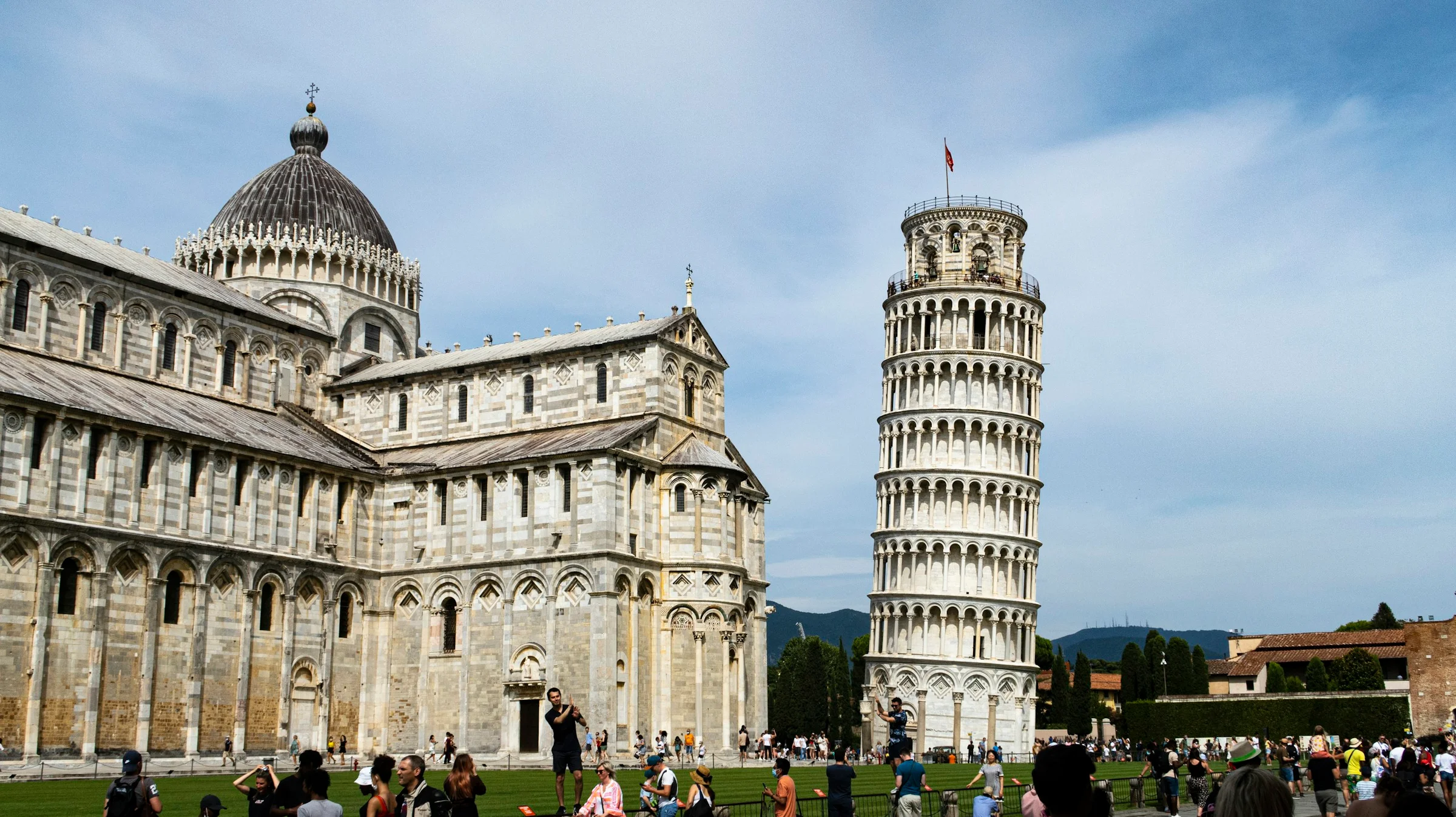 Menara Miring dan Katedral Pisa di Piazza dei Miracoli dengan langit pucat.