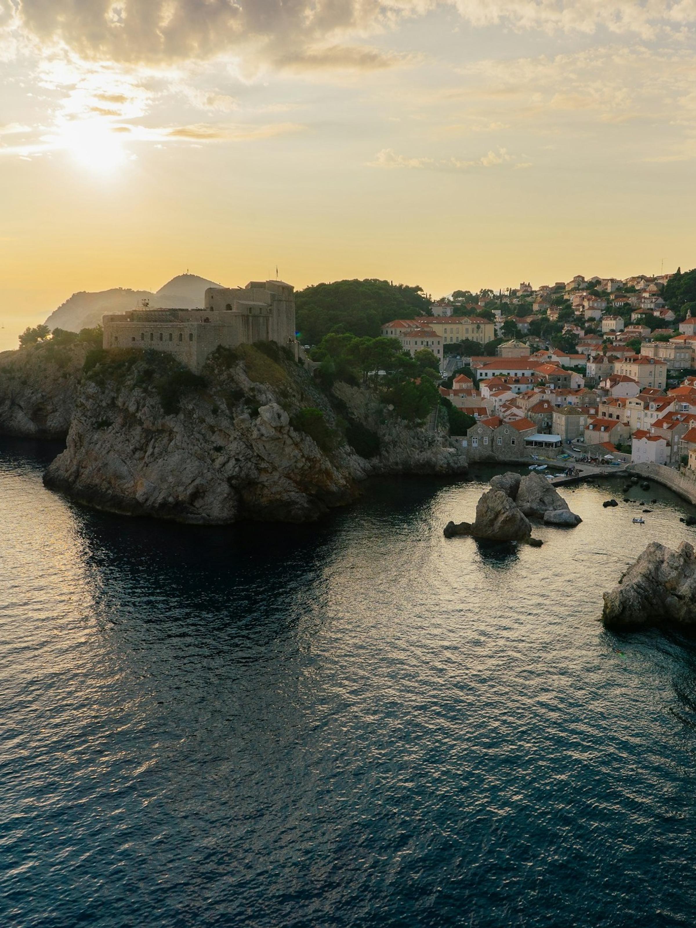 Benteng Lovrijenac Dubrovnik di atas tebing karang dengan cahaya keemasan sore.