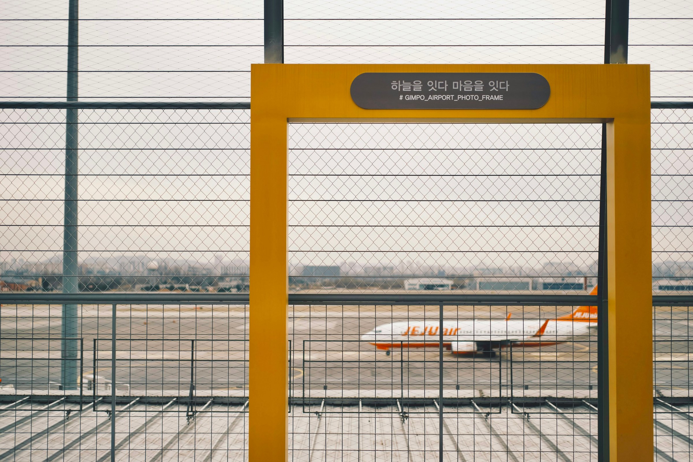 Jendela terminal Bandara Gimpo Seoul dengan pesawat Jeju Air di landasan
