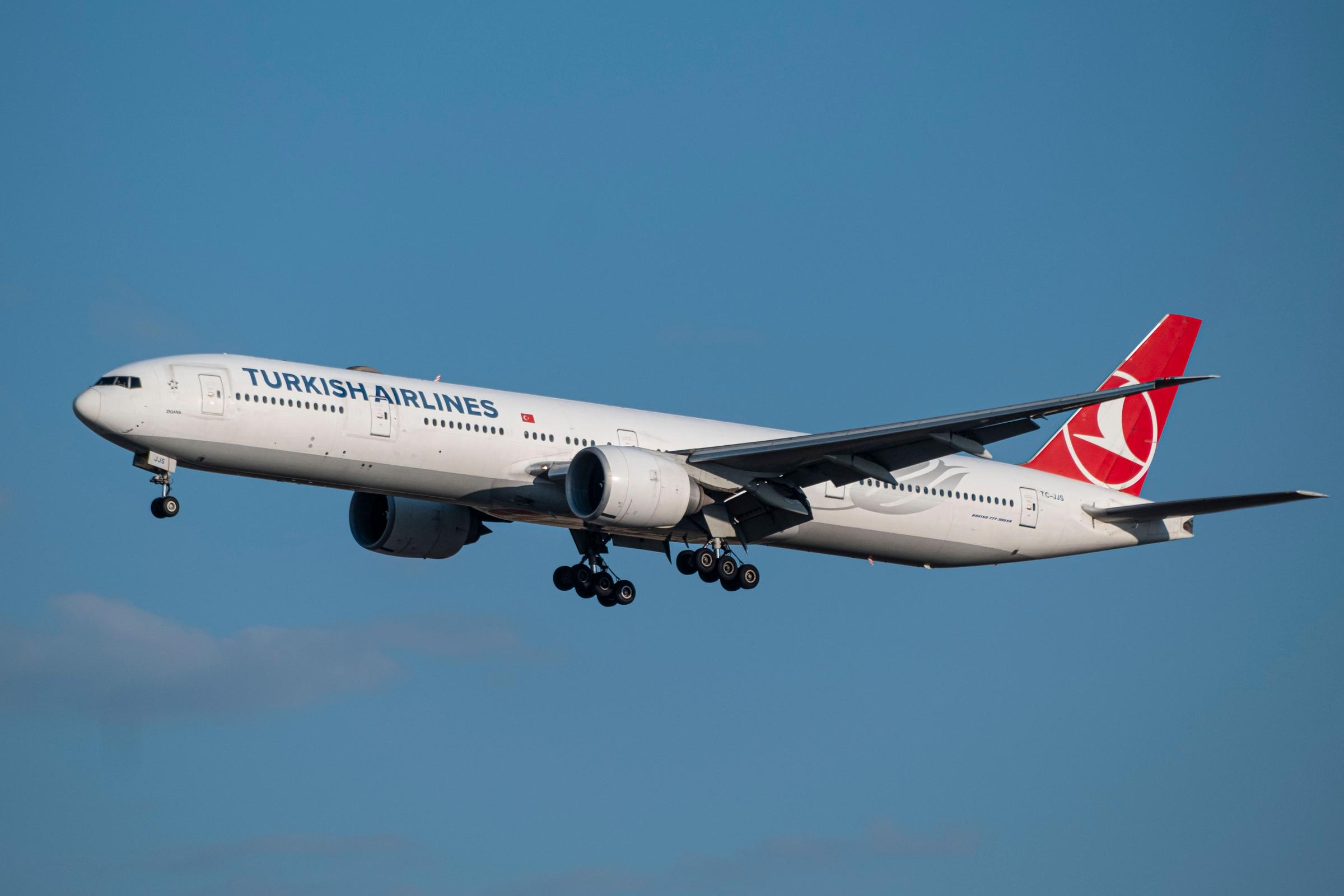 Pesawat Turkish Airlines Boeing 777 lepas landas dengan roda masih terbuka di langit biru cerah