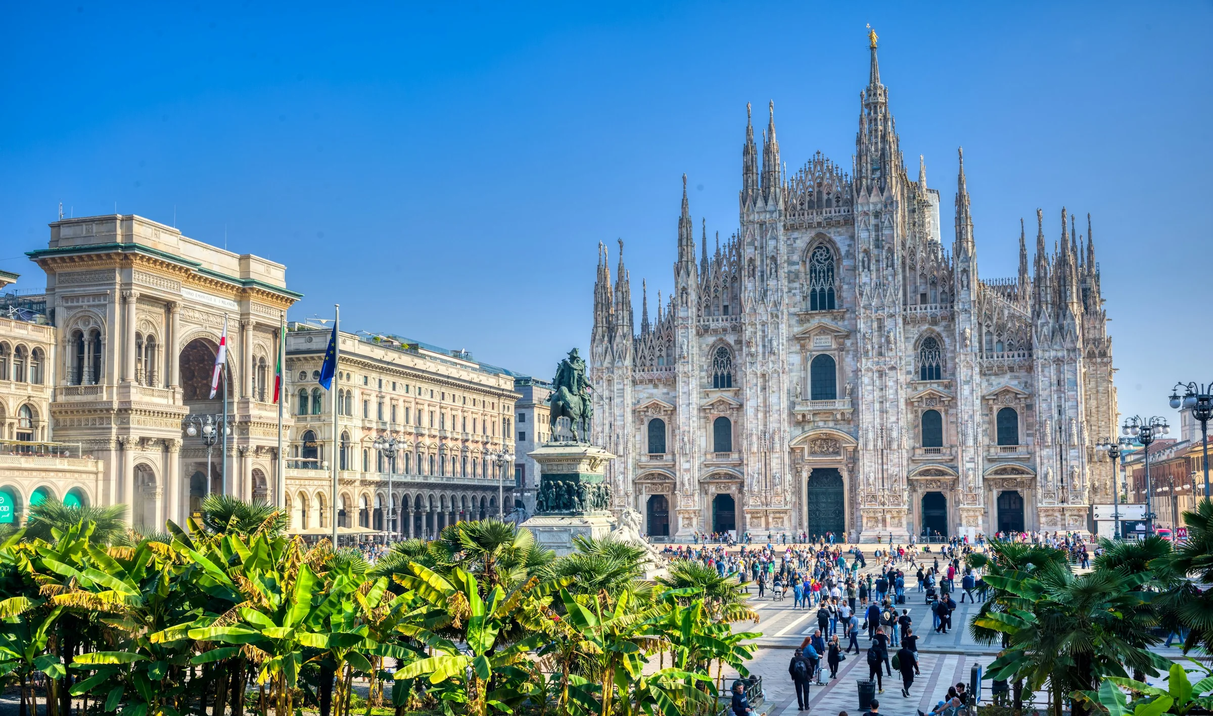 Duomo di Milano dan Galleria di Piazza del Duomo dengan palem dan langit biru cerah.