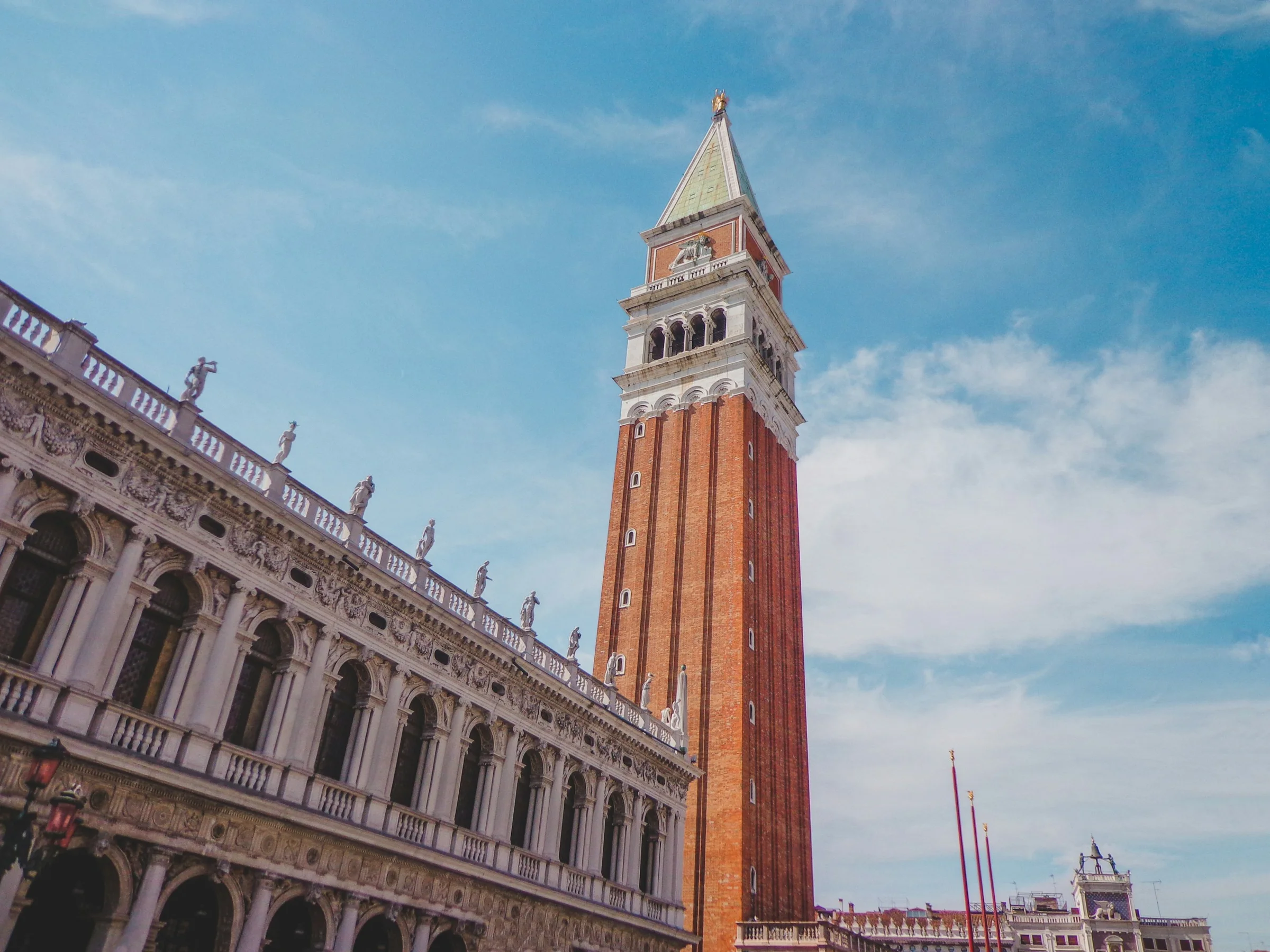 Campanile San Marco dan Biblioteca Marciana di Venice dengan langit biru berawan.