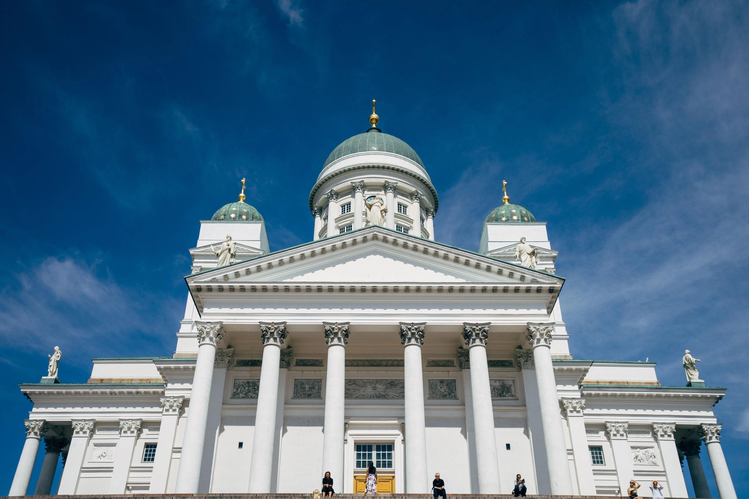 Katedral Helsinki berwarna putih dengan kubah hijau menjulang di bawah langit biru cerah