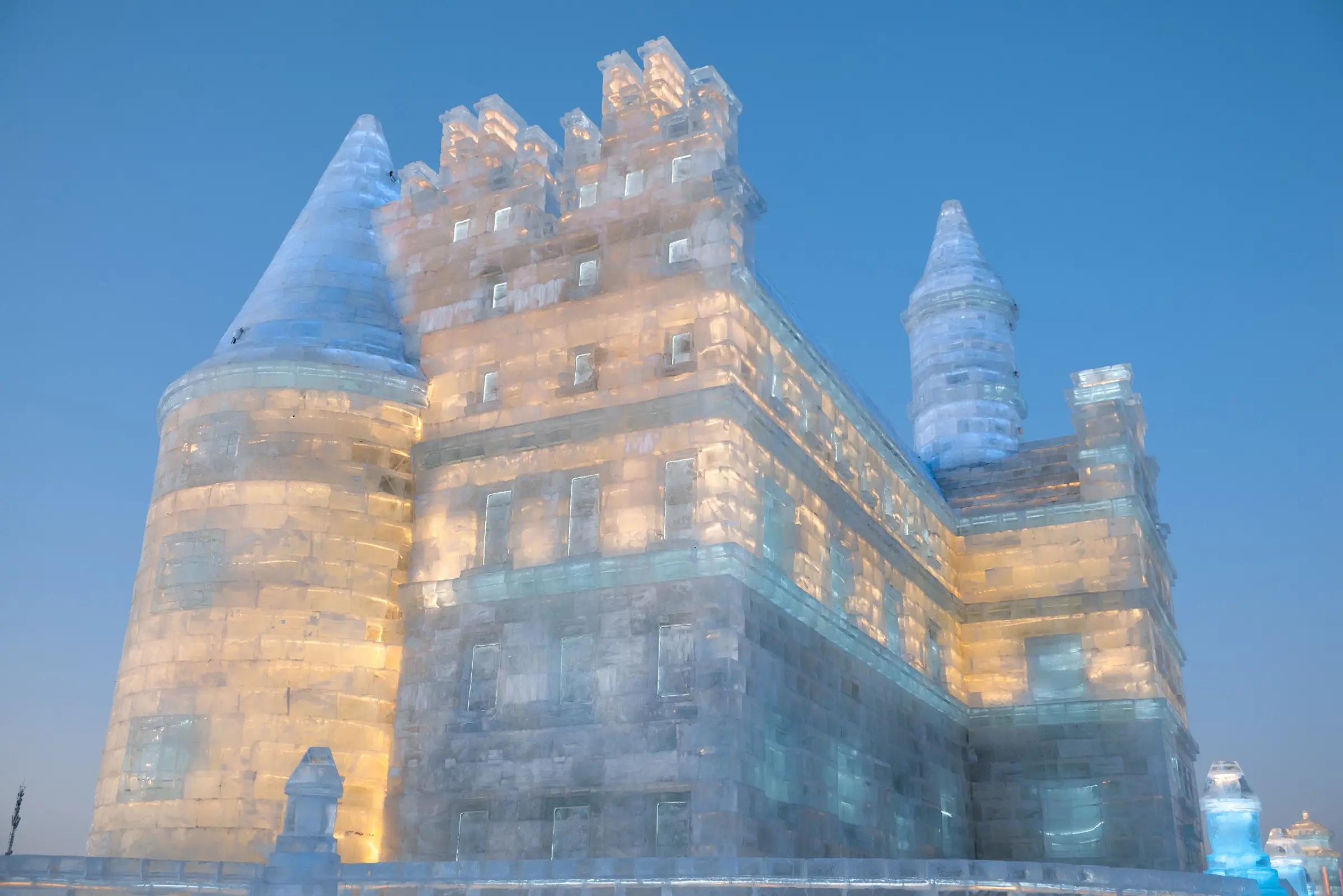 Istana es raksasa menyala warna-warni di ajang Harbin Ice Festival pada senja musim dingin