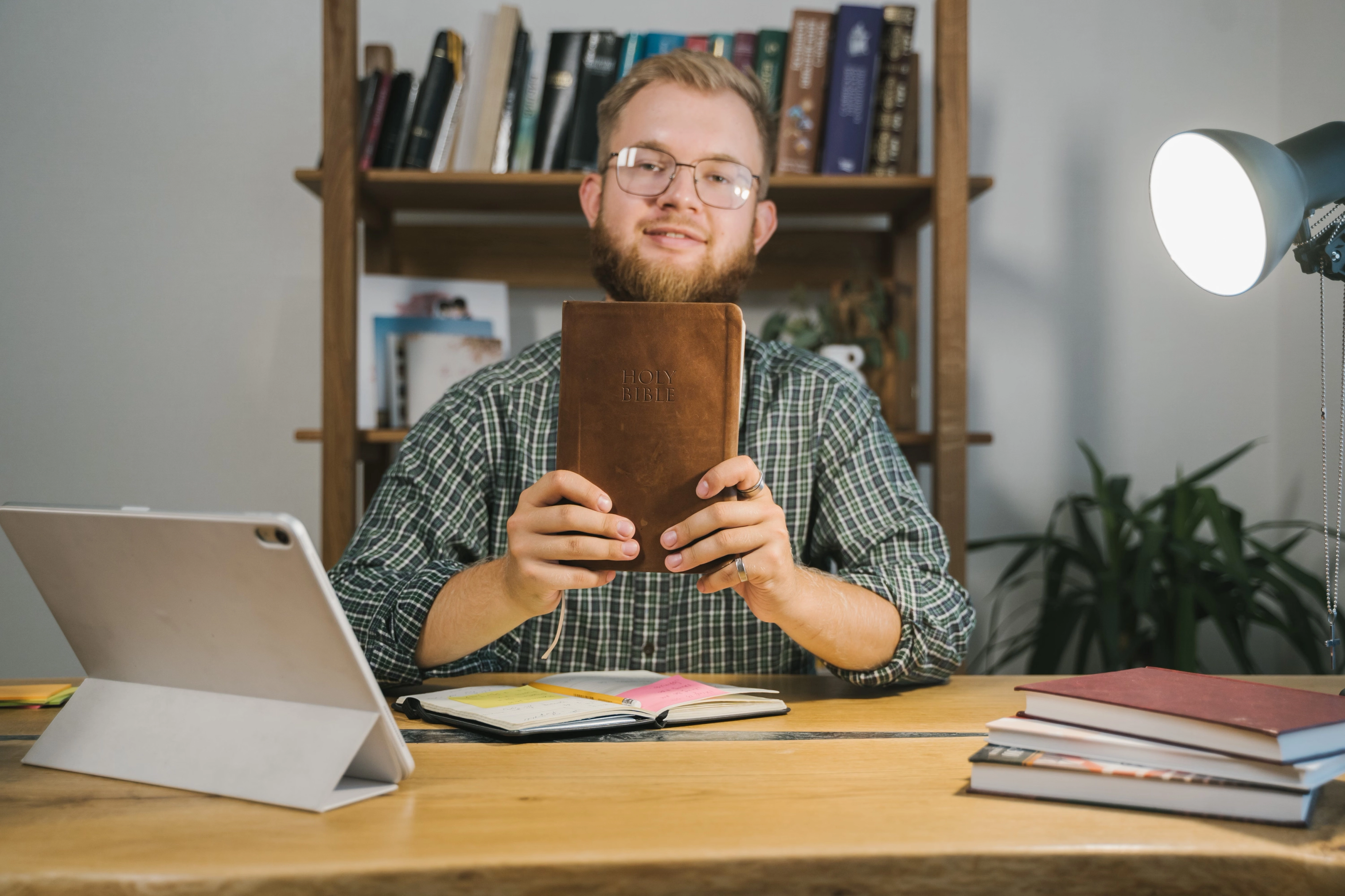 A man studying the Bible with notes at a desk