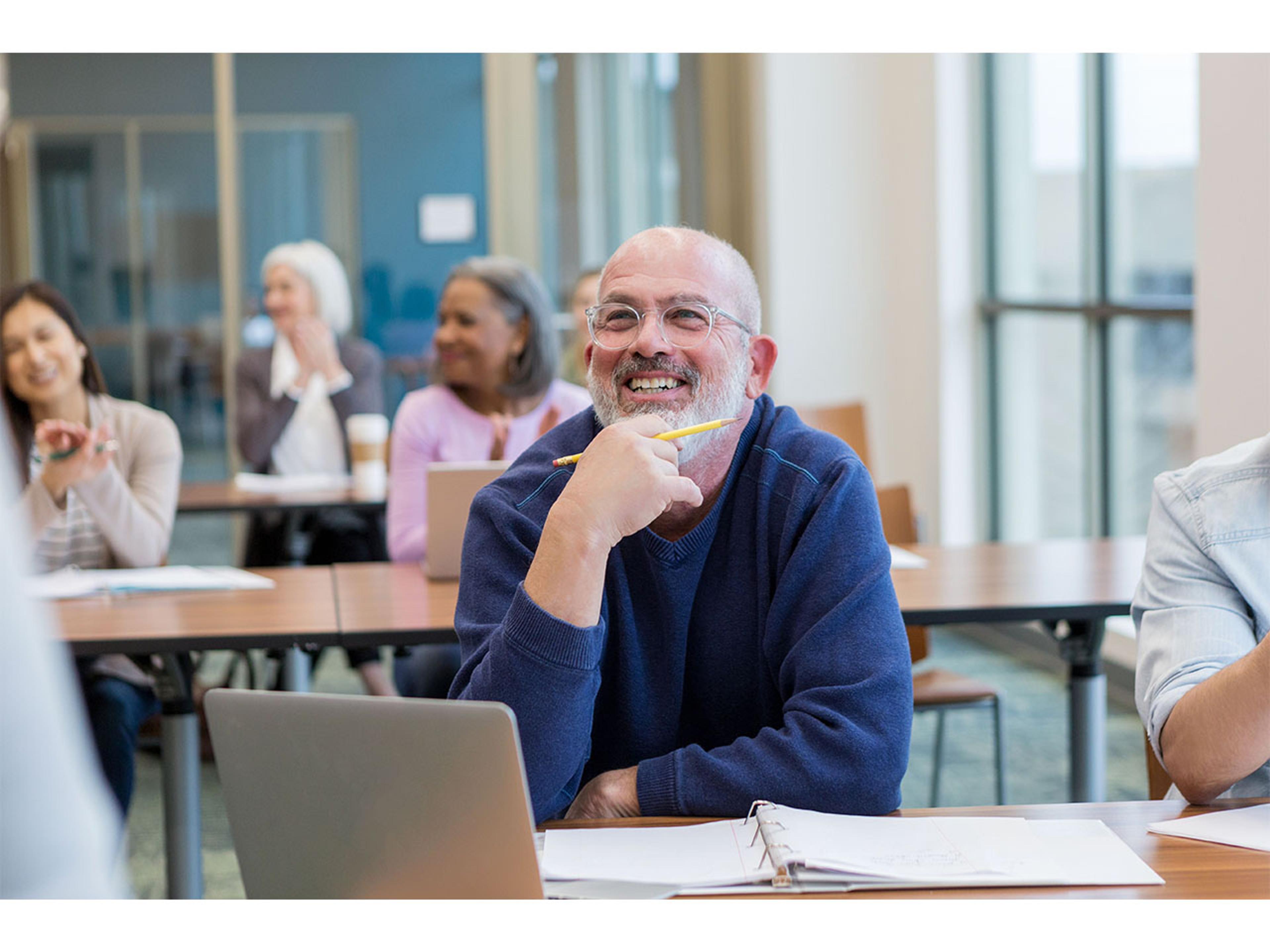 En gruppe mennesker i et undervisningslokale. Smilende mann sitter først.