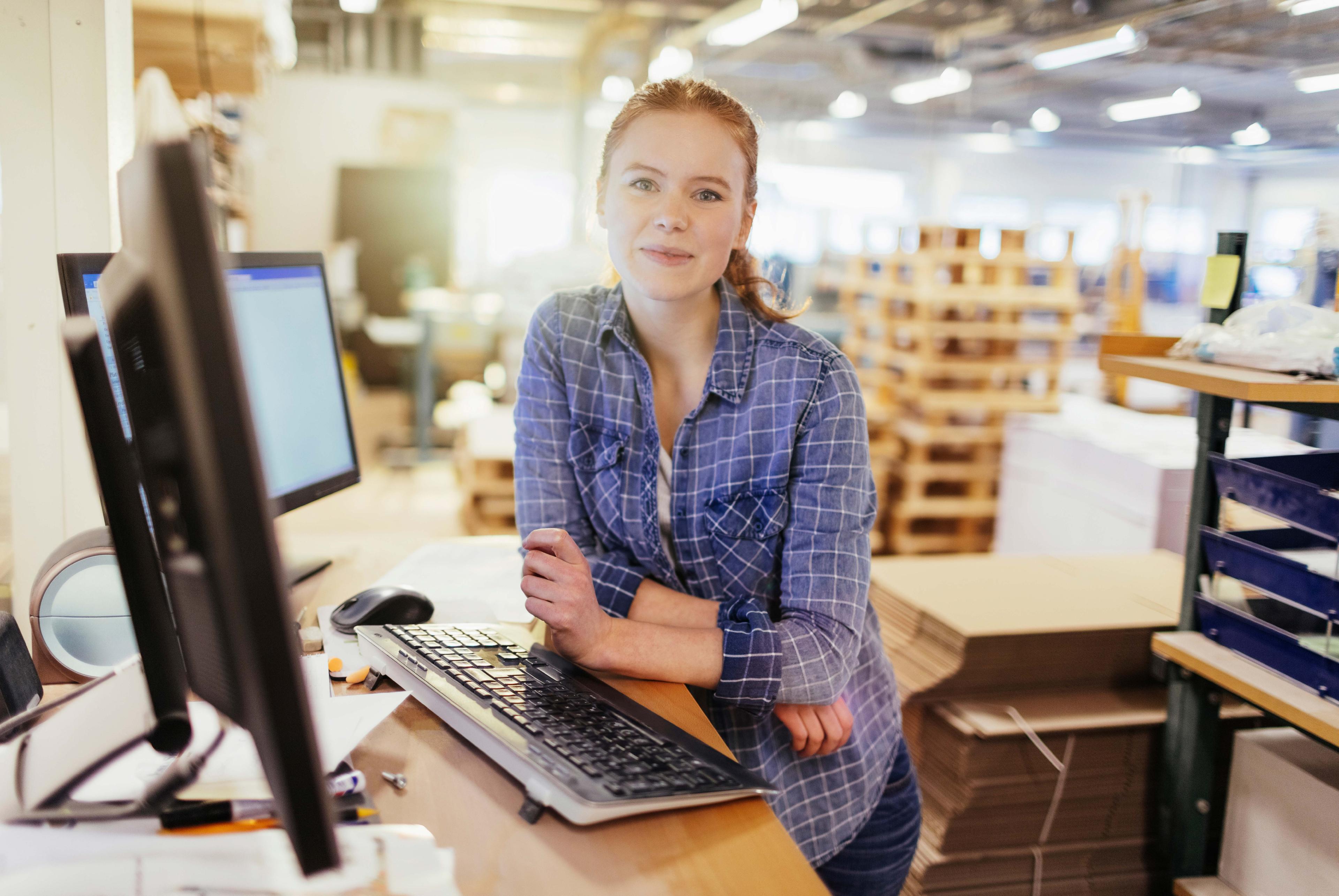 Smilende dame med skjorte forran en datamaskin