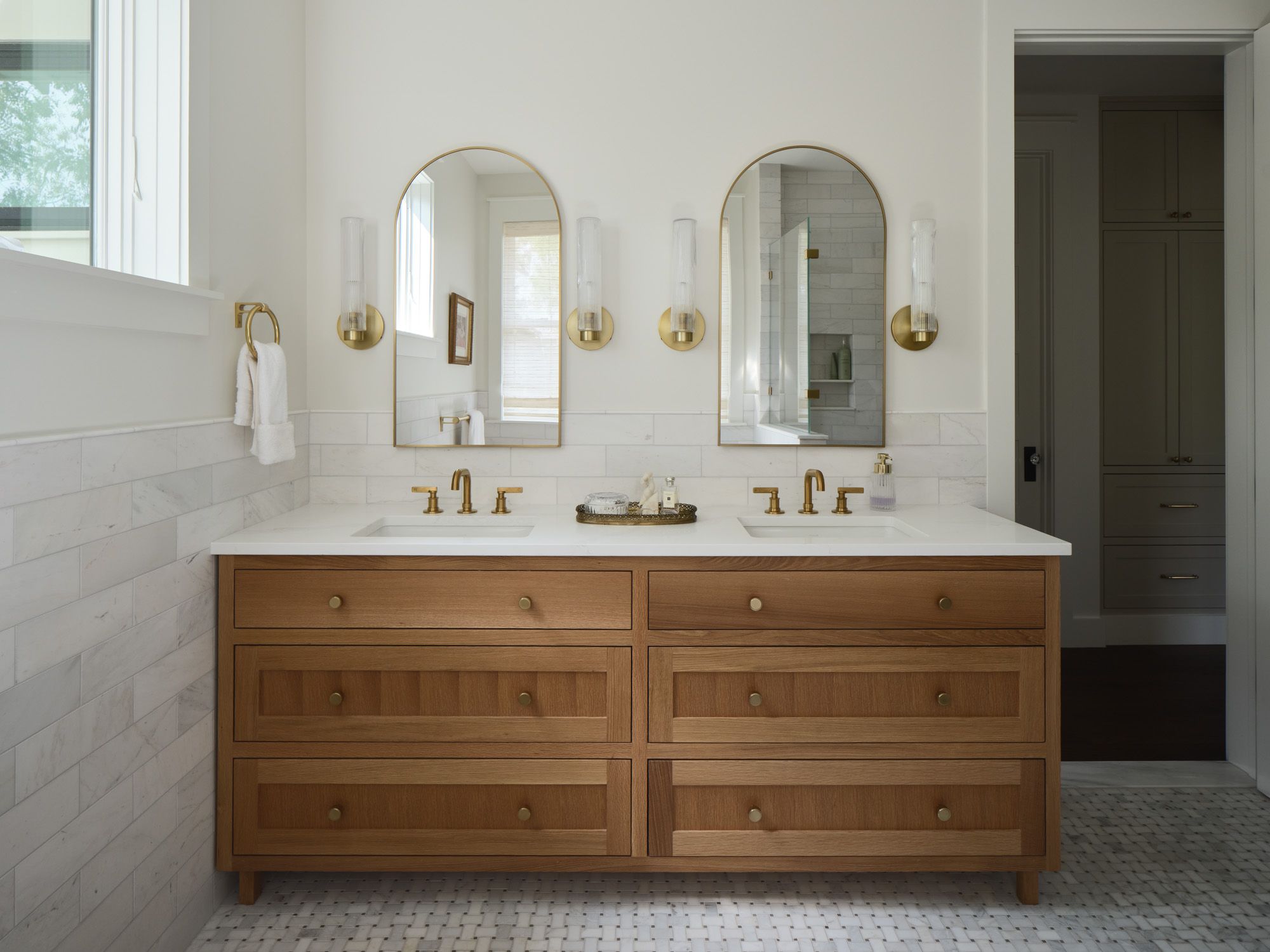 Bathroom vanity with two sinks, arched mirrors and wooden drawers