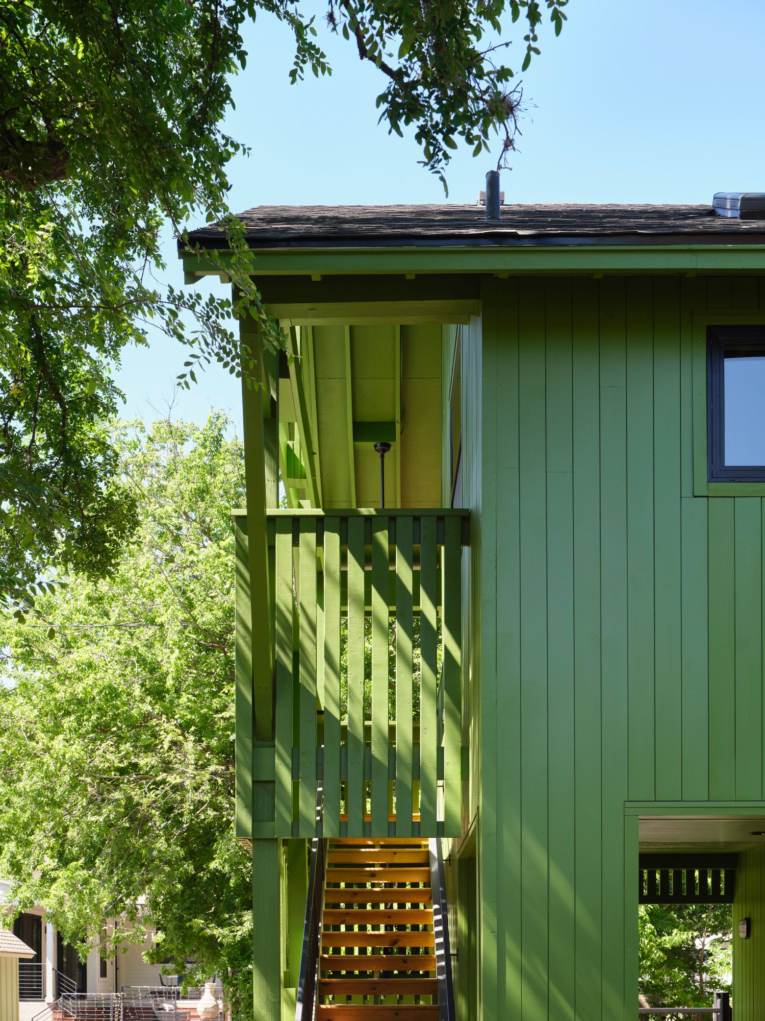 Green house exterior with an enclosed staircase surrounded by trees