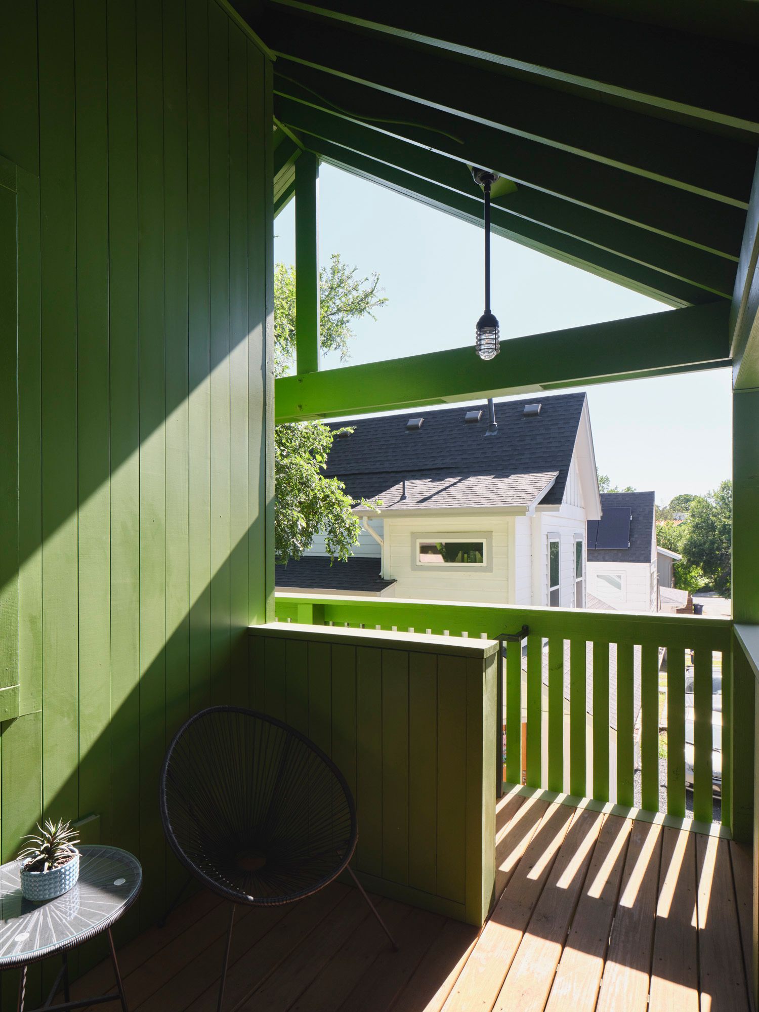 Covered balcony with chair, side table, railing and hanging light