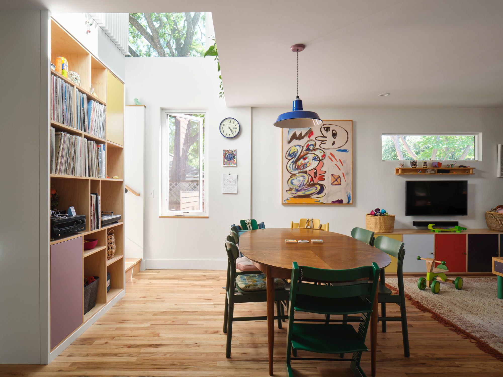 Dining and playroom with wooden table, bookshelves, television and children's toys