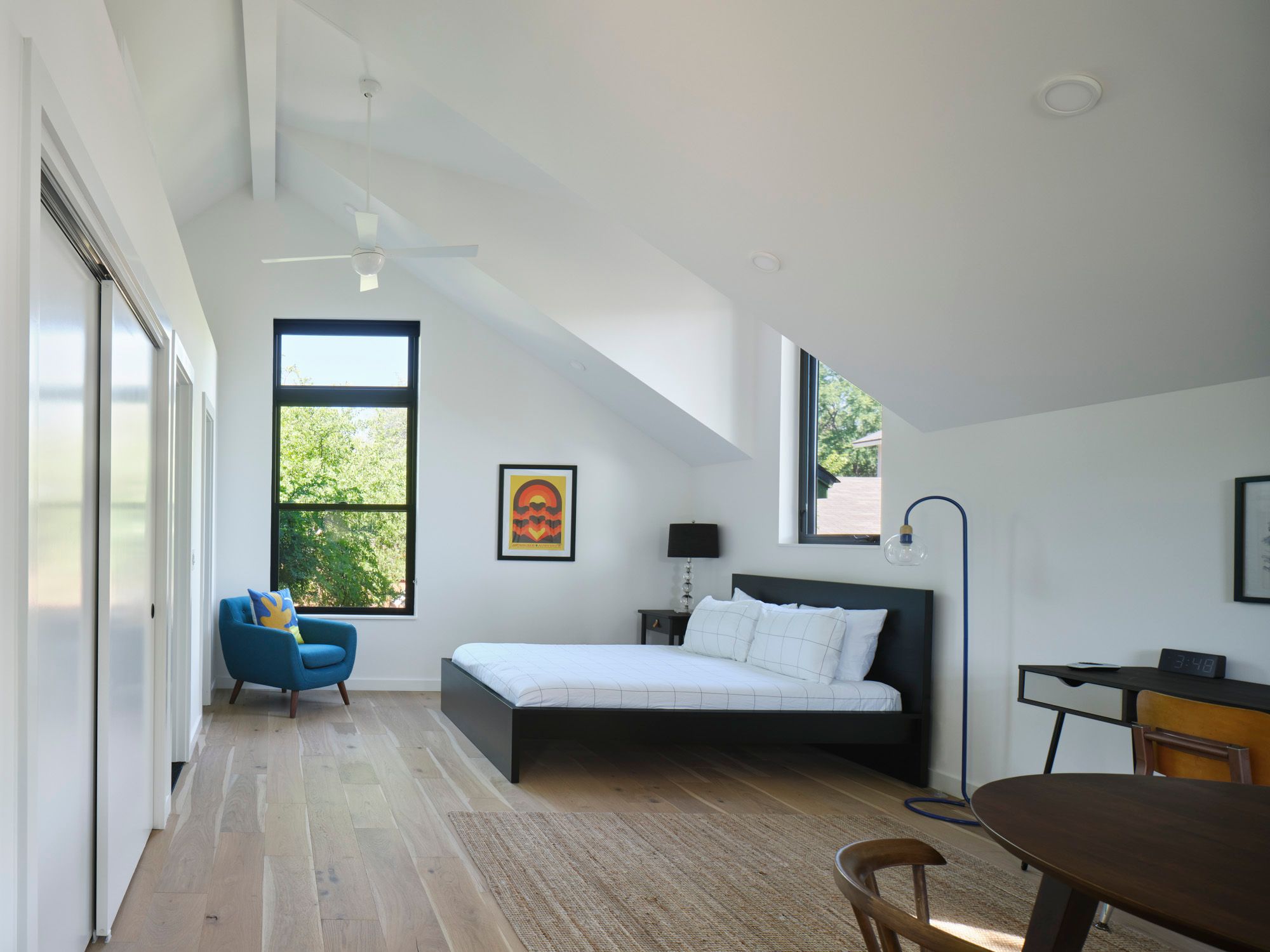 Bedroom with vaulted ceiling, bed, armchair, desk and dining table