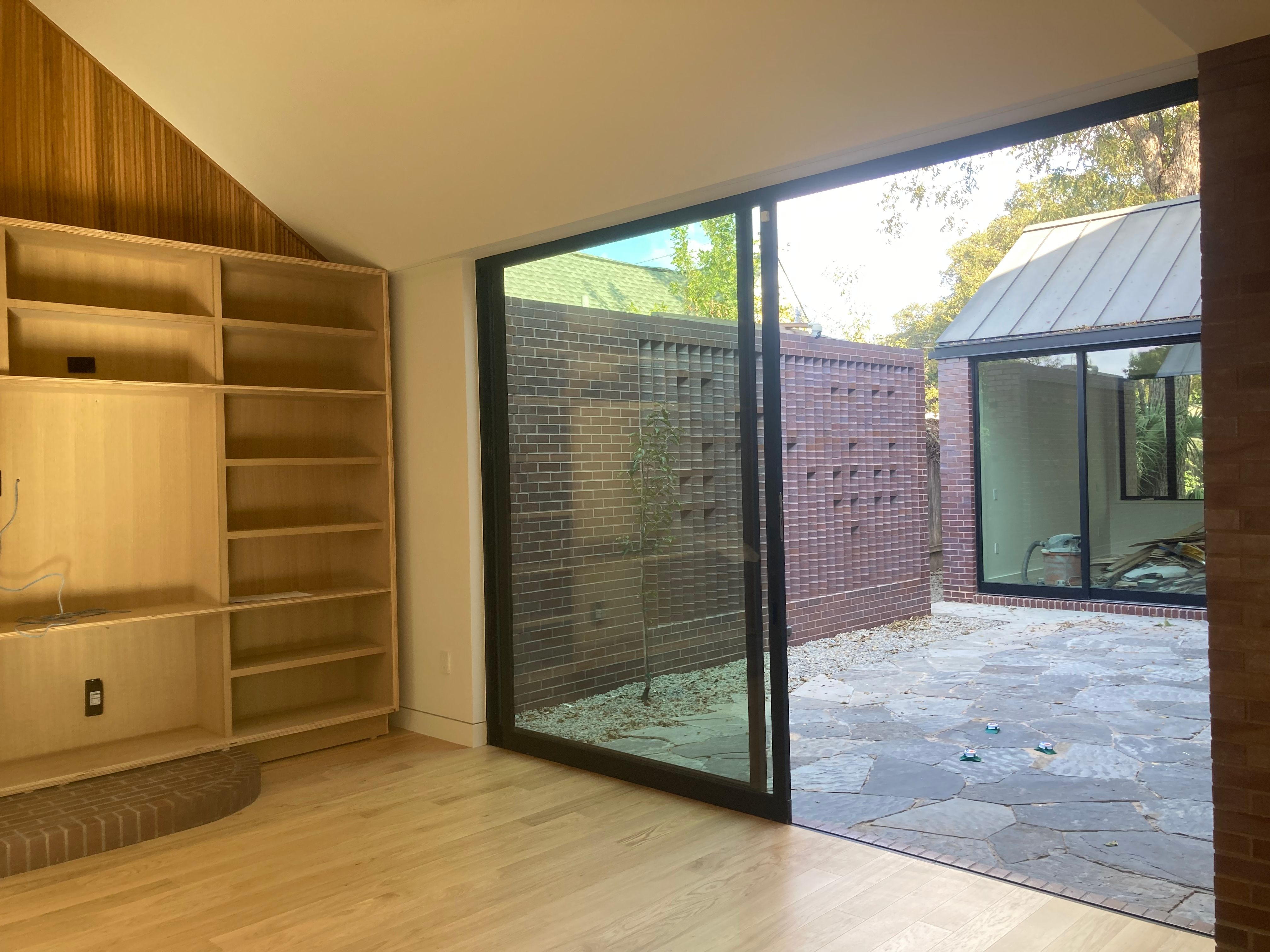 Living room with built-in shelving and glass doors opening to courtyard