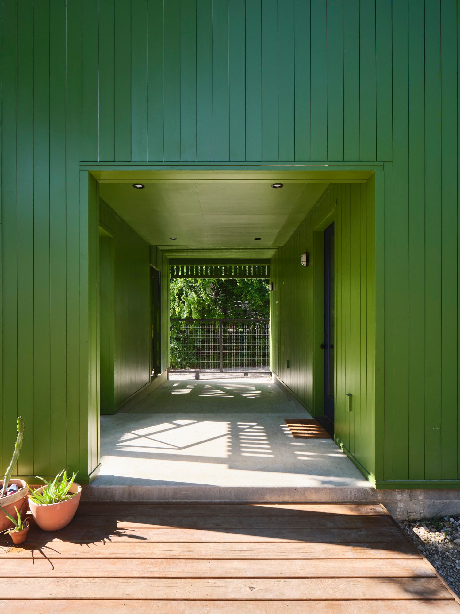 Covered passage through a green-paneled building leads to a gated deck