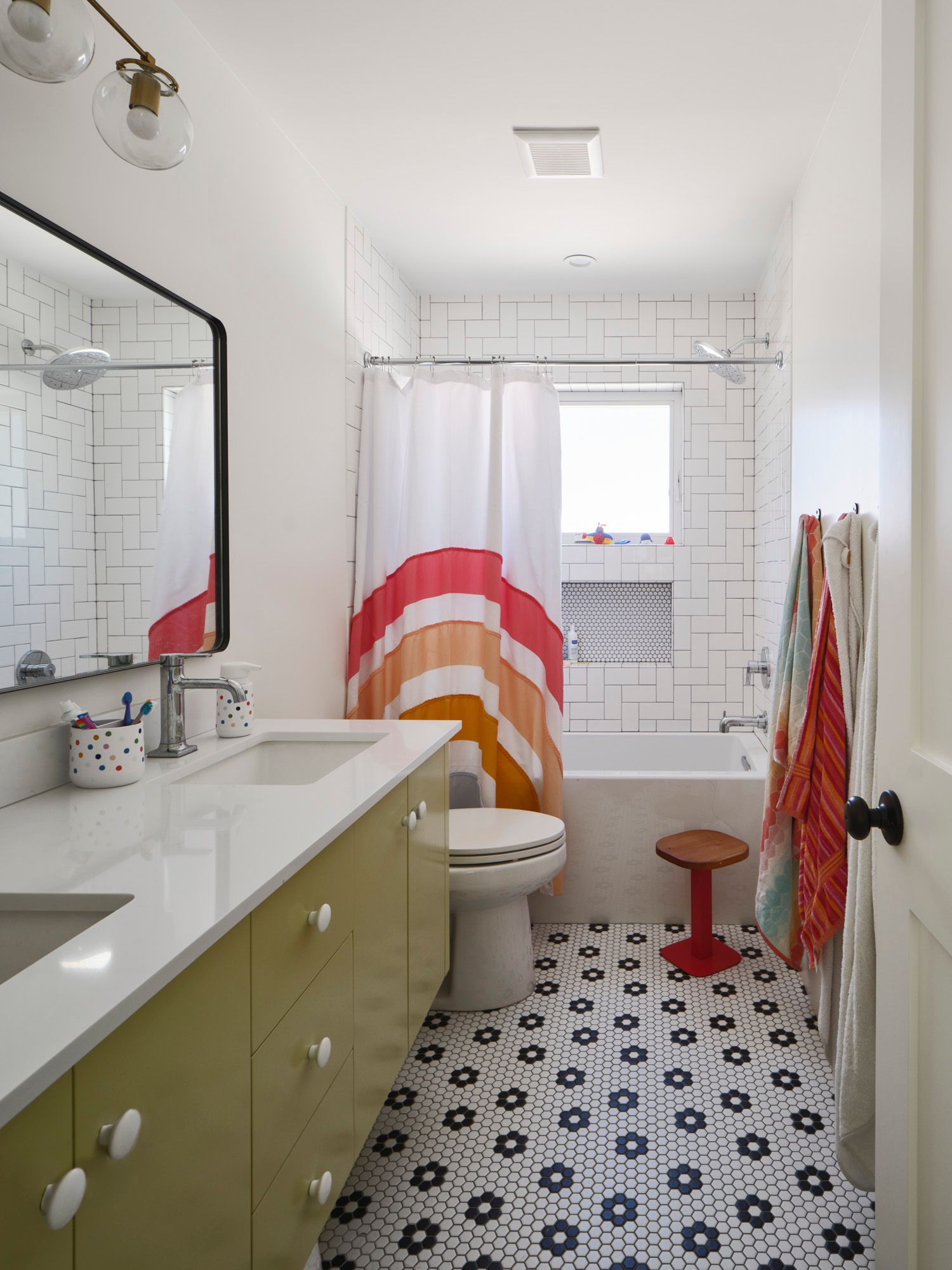 Bathroom with double vanity, bathtub, striped shower curtain and patterned tile floor