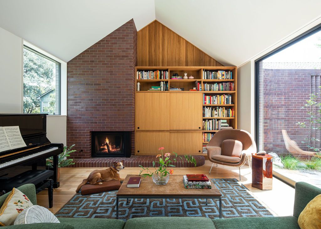 Dog rests in a living room with fireplace, piano and bookshelves