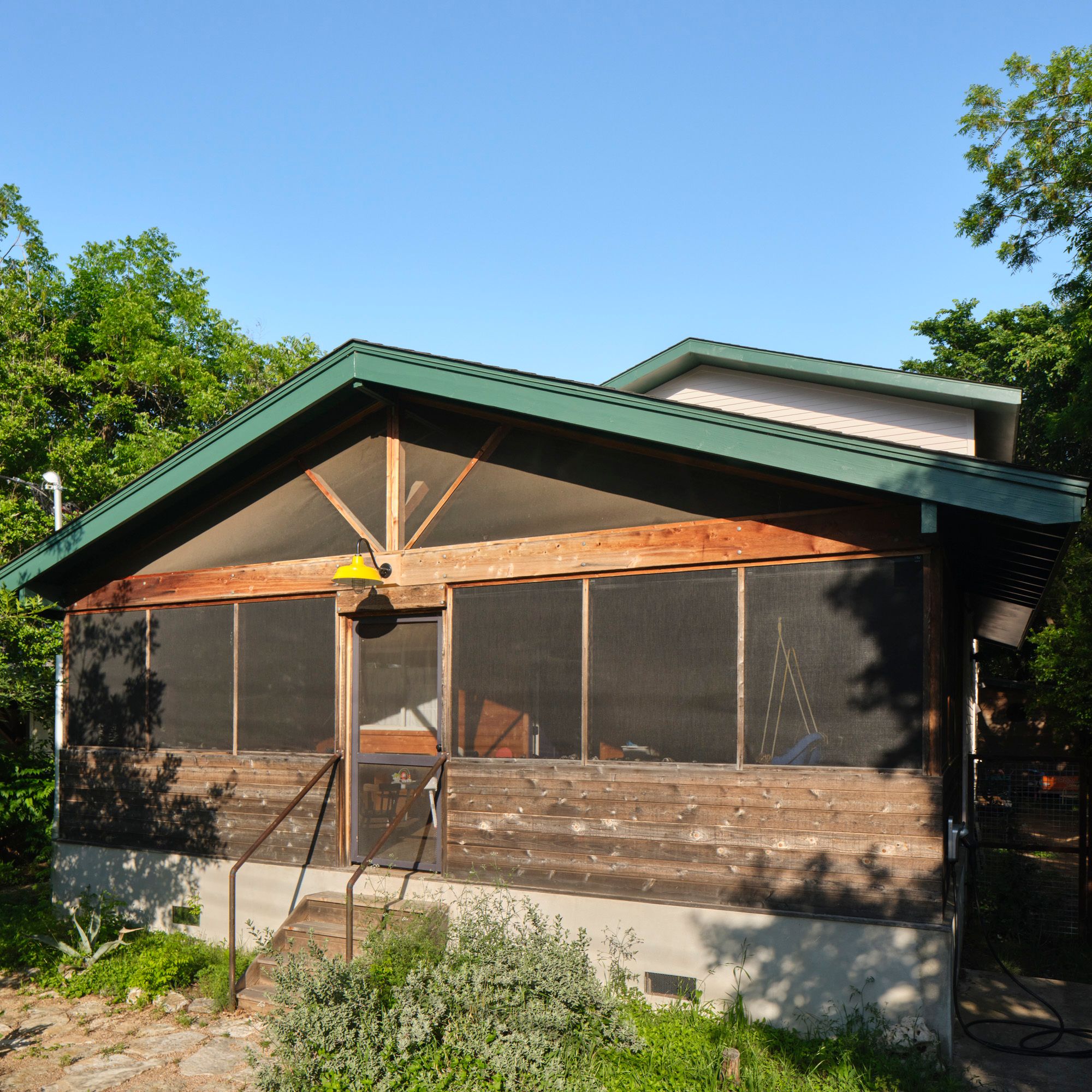 Screened wooden porch with steps and a green gabled roof