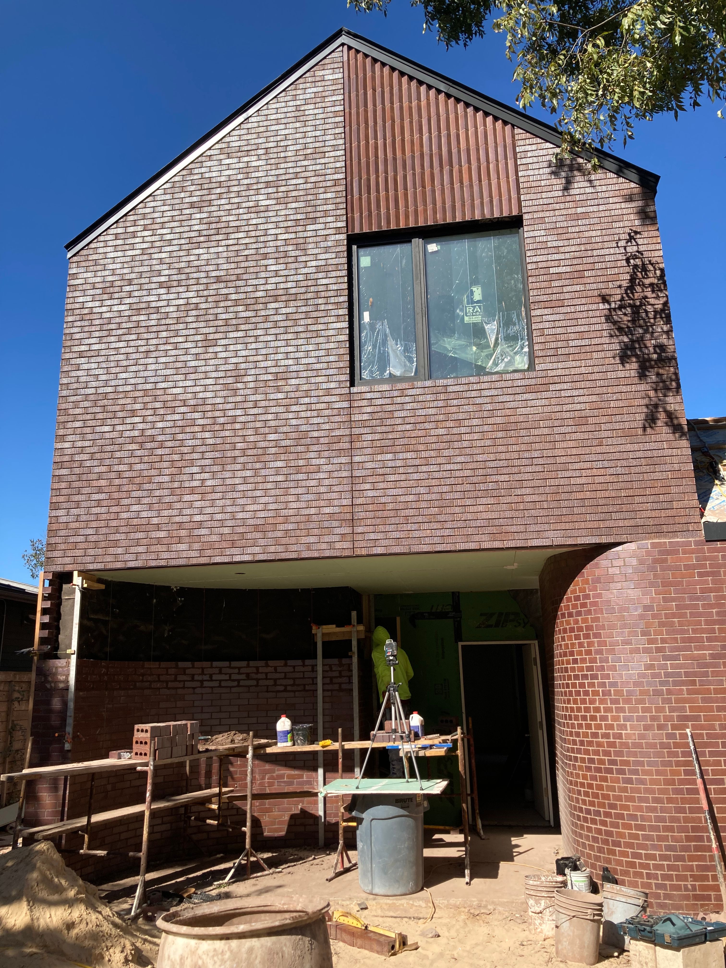 Brick-clad house under construction with scaffolding and building materials