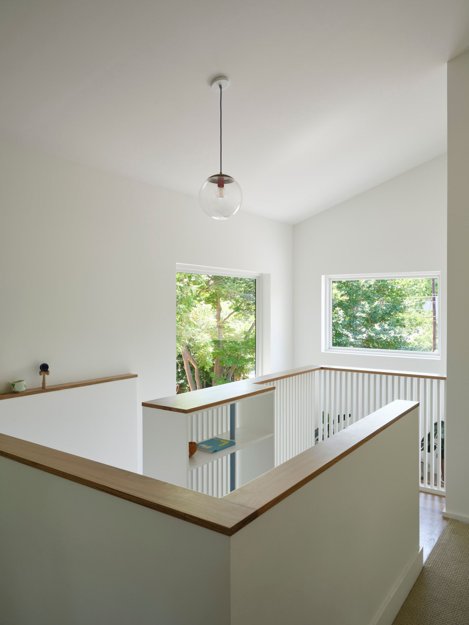 Upstairs landing with wood-capped railings and windows overlooking trees