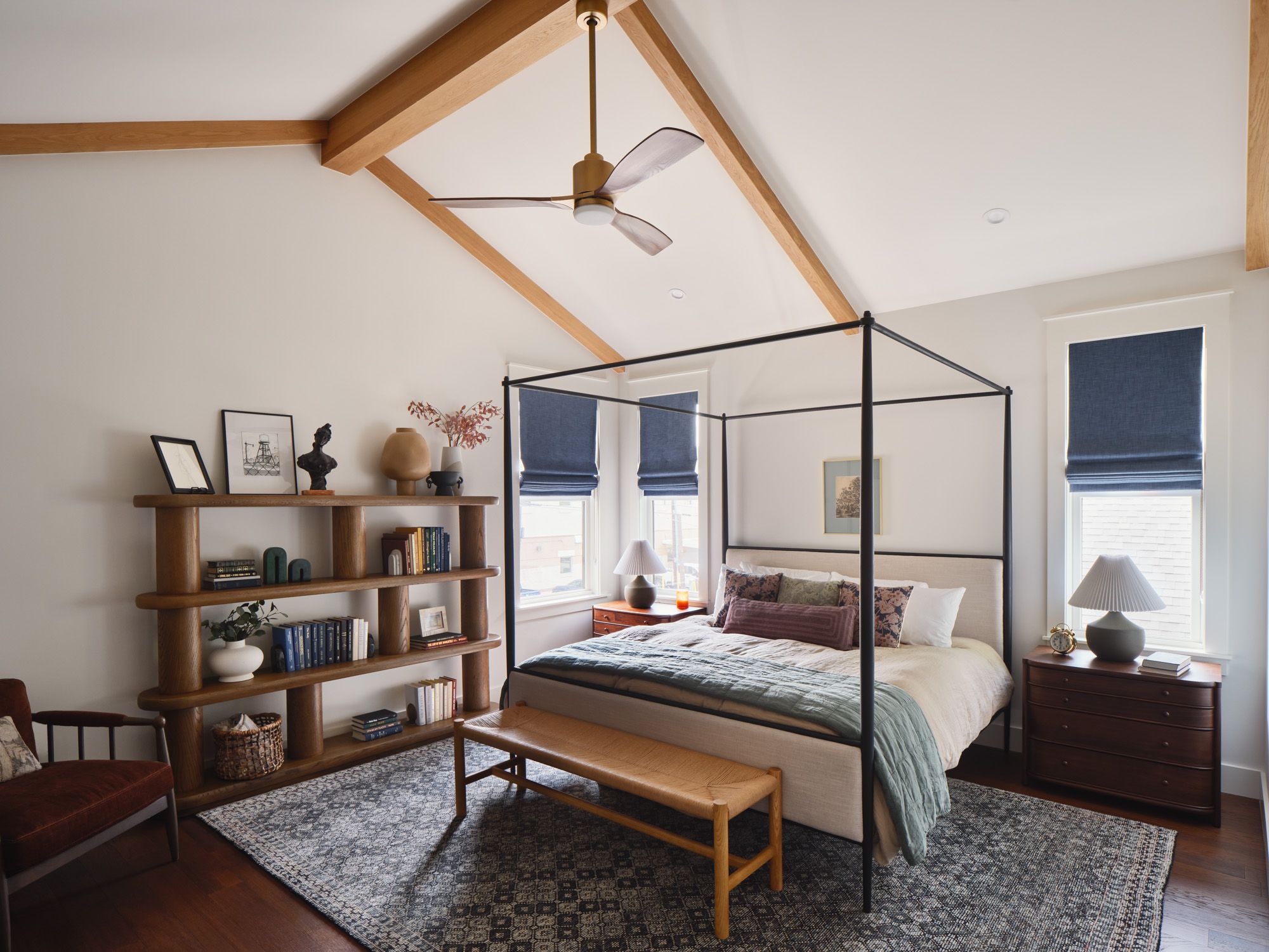 Bedroom with canopy bed, exposed beams, bookshelf and window shades