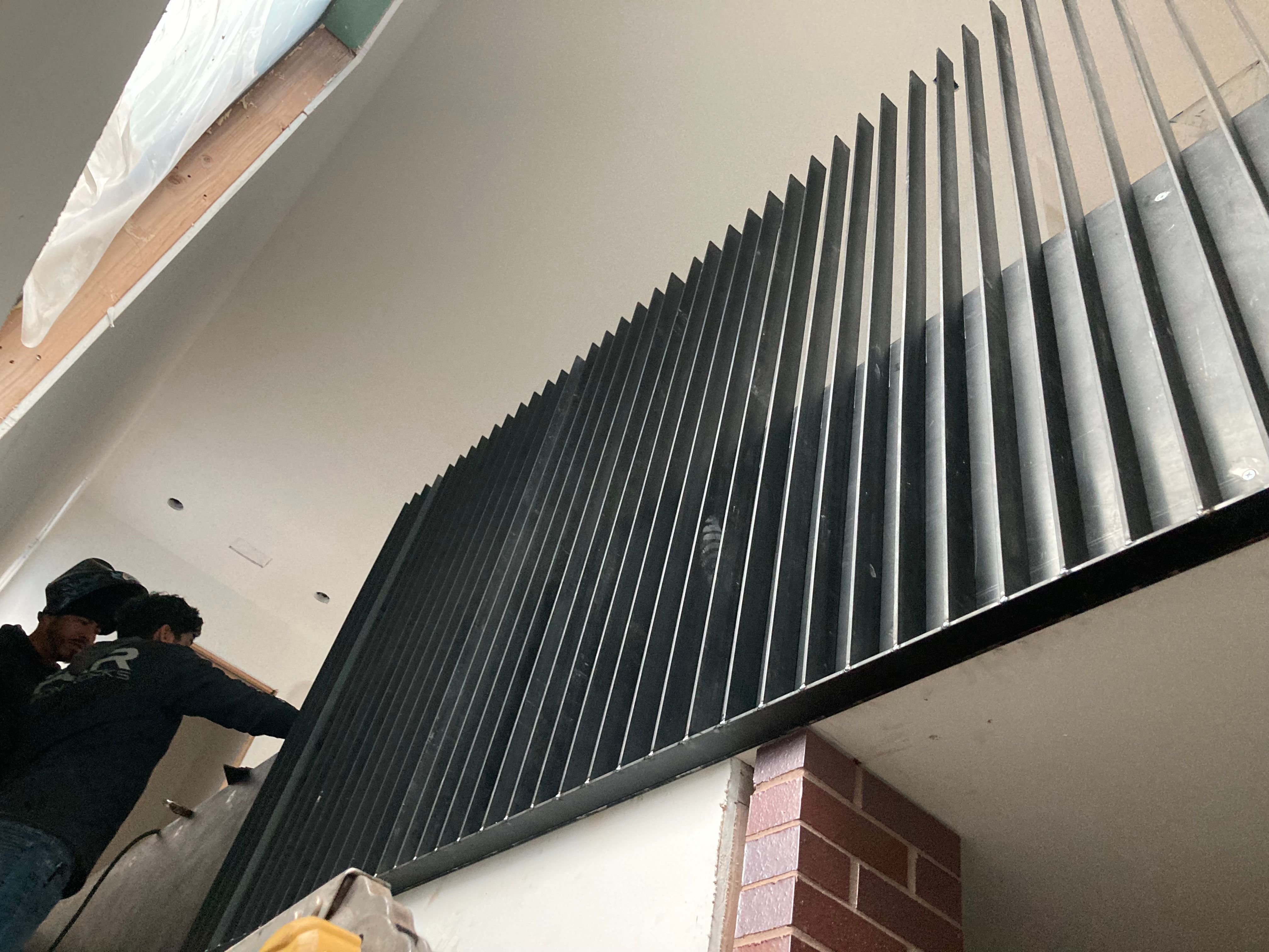 Workers install vertical metal slats inside a building