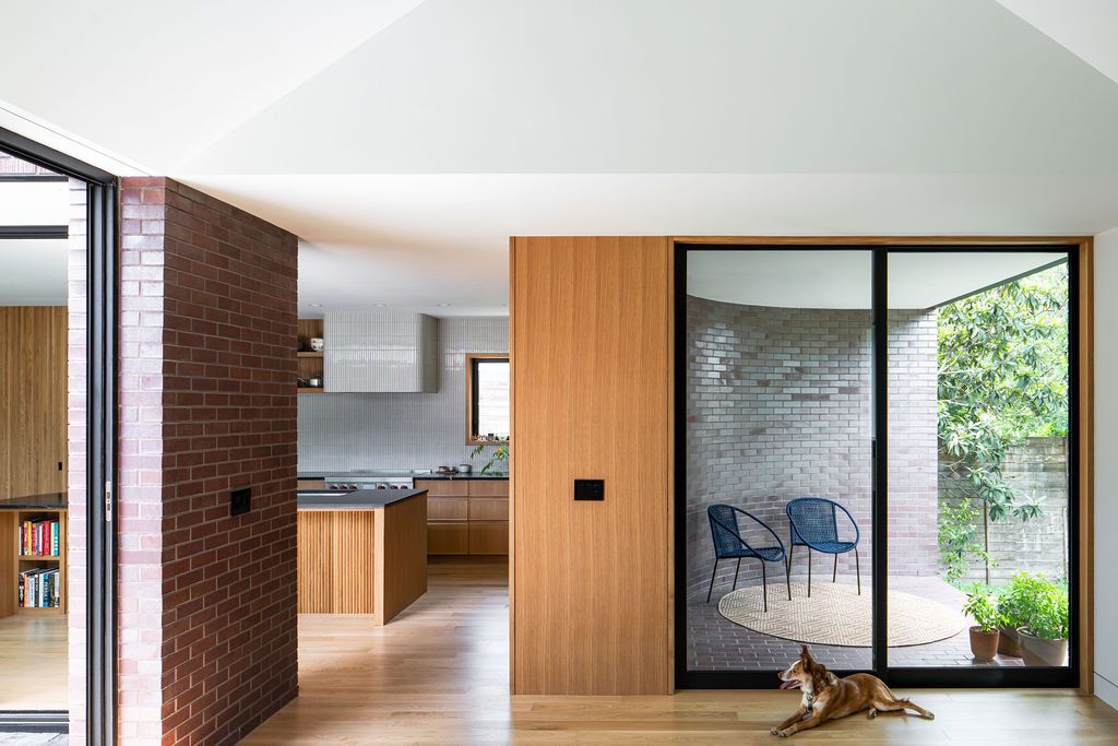 Dog rests beside glass doors overlooking a brick courtyard