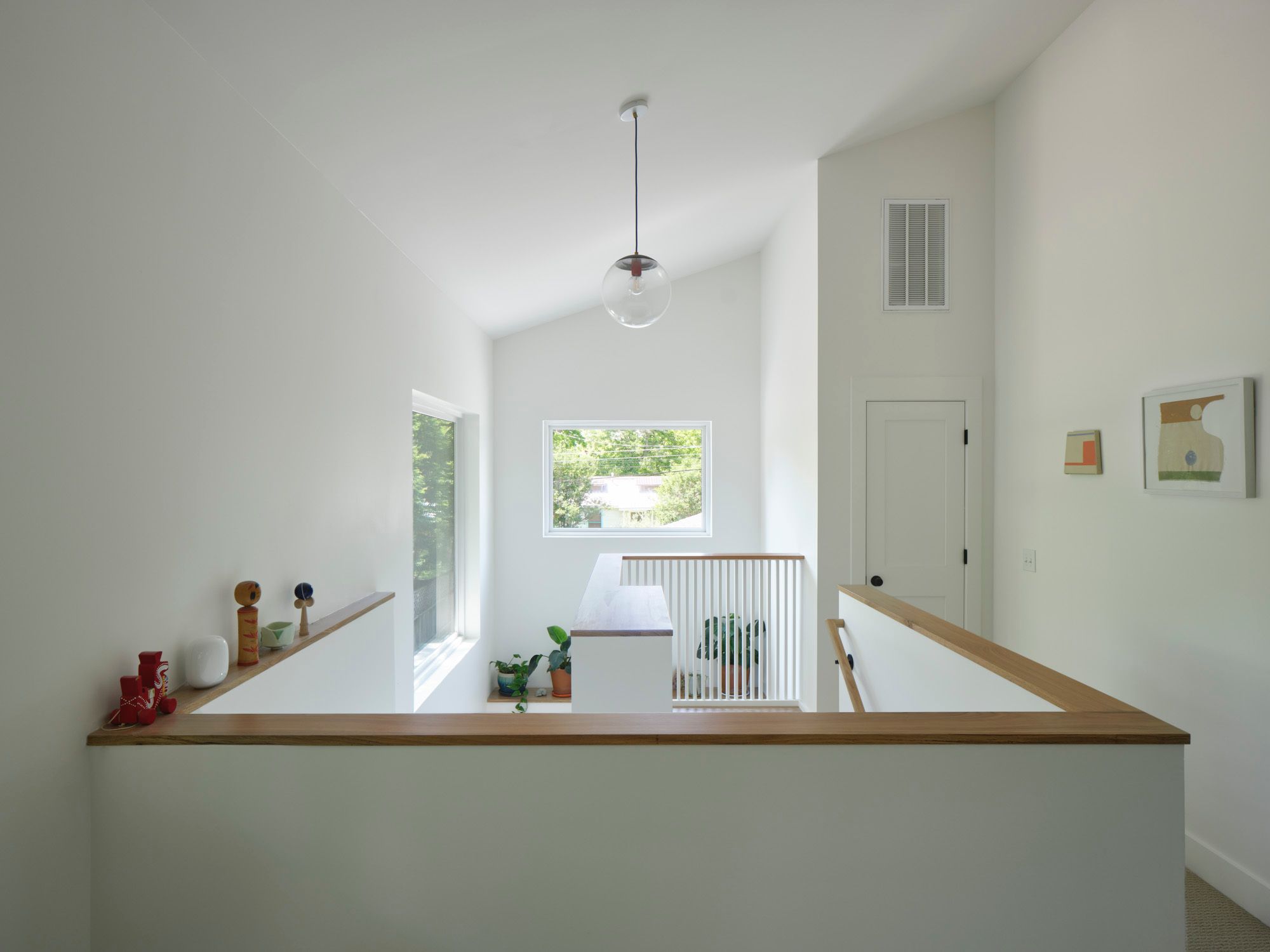 Upstairs landing with wood-trimmed railings, windows and pendant light