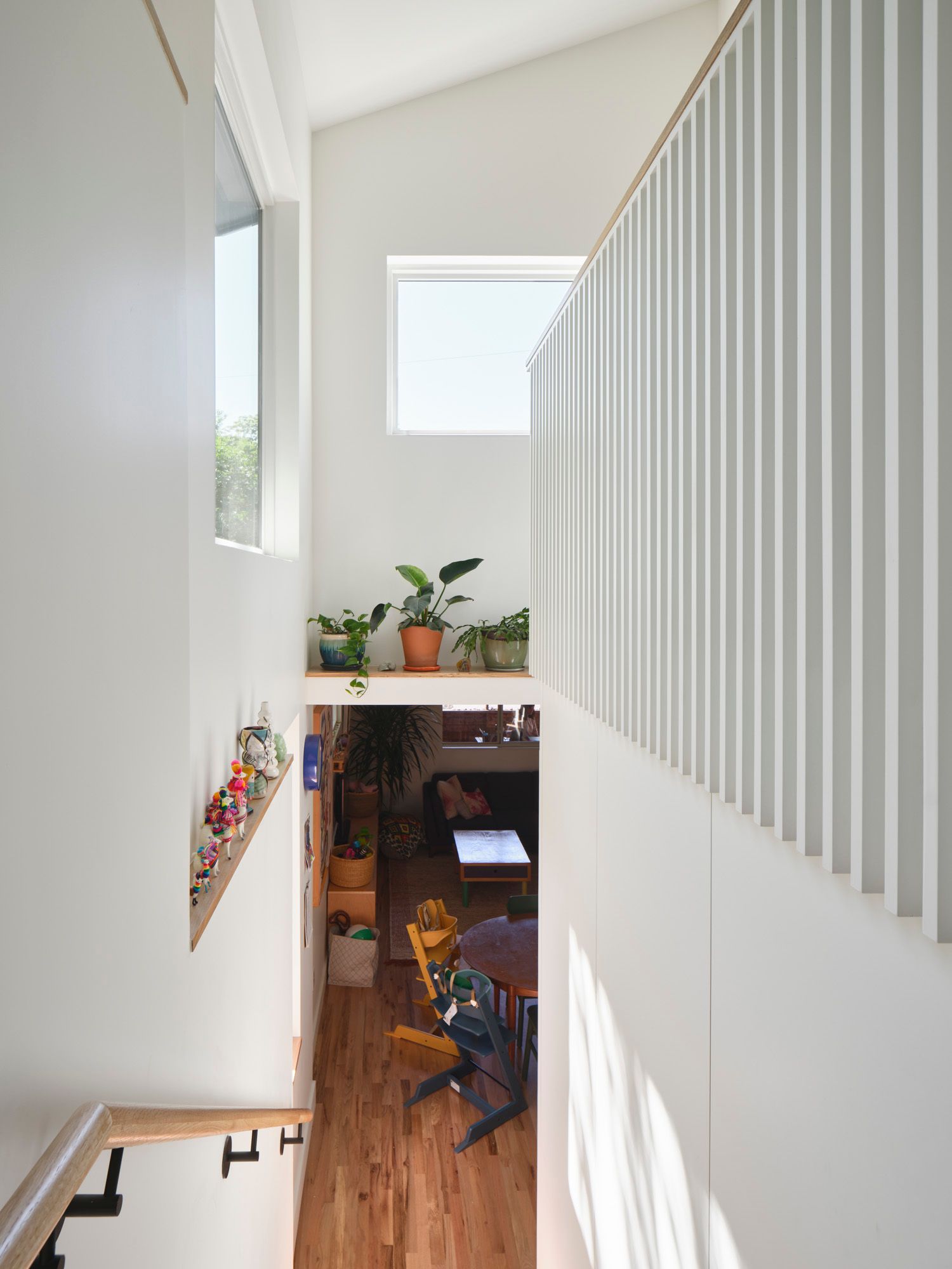 Stairwell overlooks a dining area with plants and children's chairs