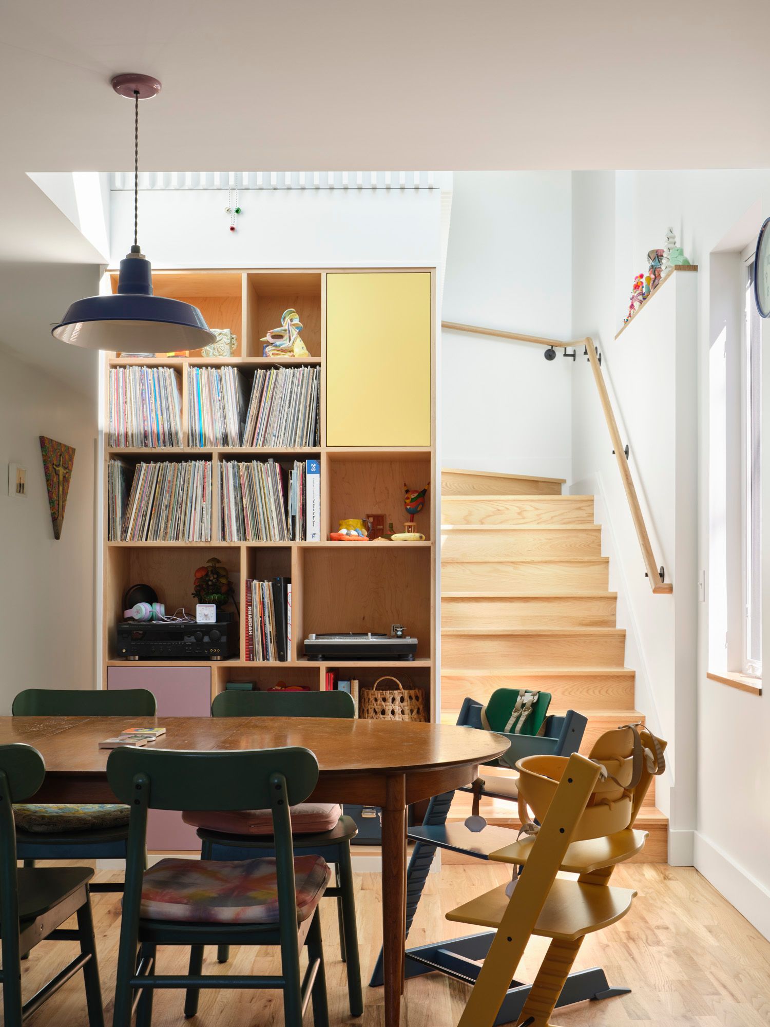 Dining area with record-filled shelving and wooden stairs
