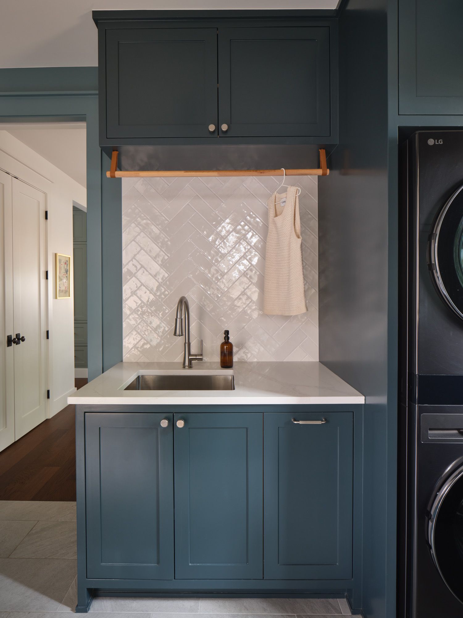 Laundry room sink with cabinetry beside a stacked washer and dryer