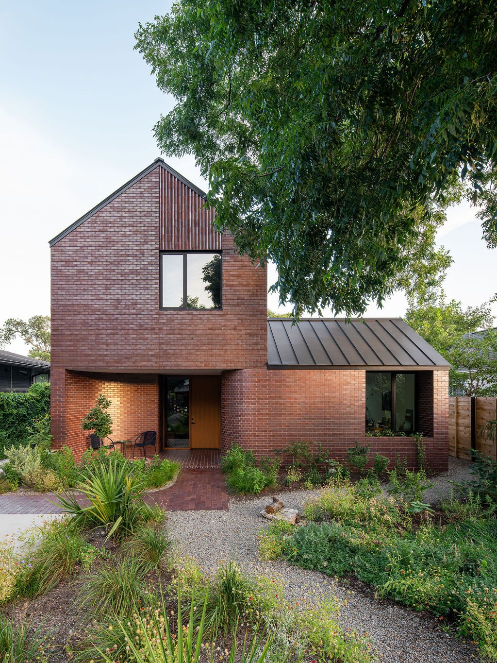 Two-story brick house with a metal roof and landscaped courtyard