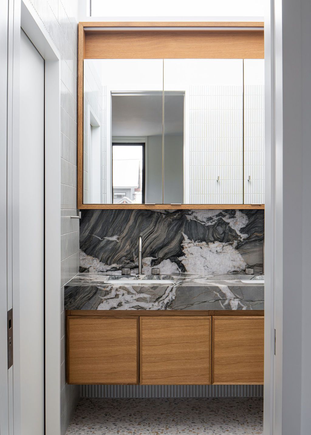 Bathroom vanity with marble surfaces, wood cabinetry and mirrored medicine cabinet