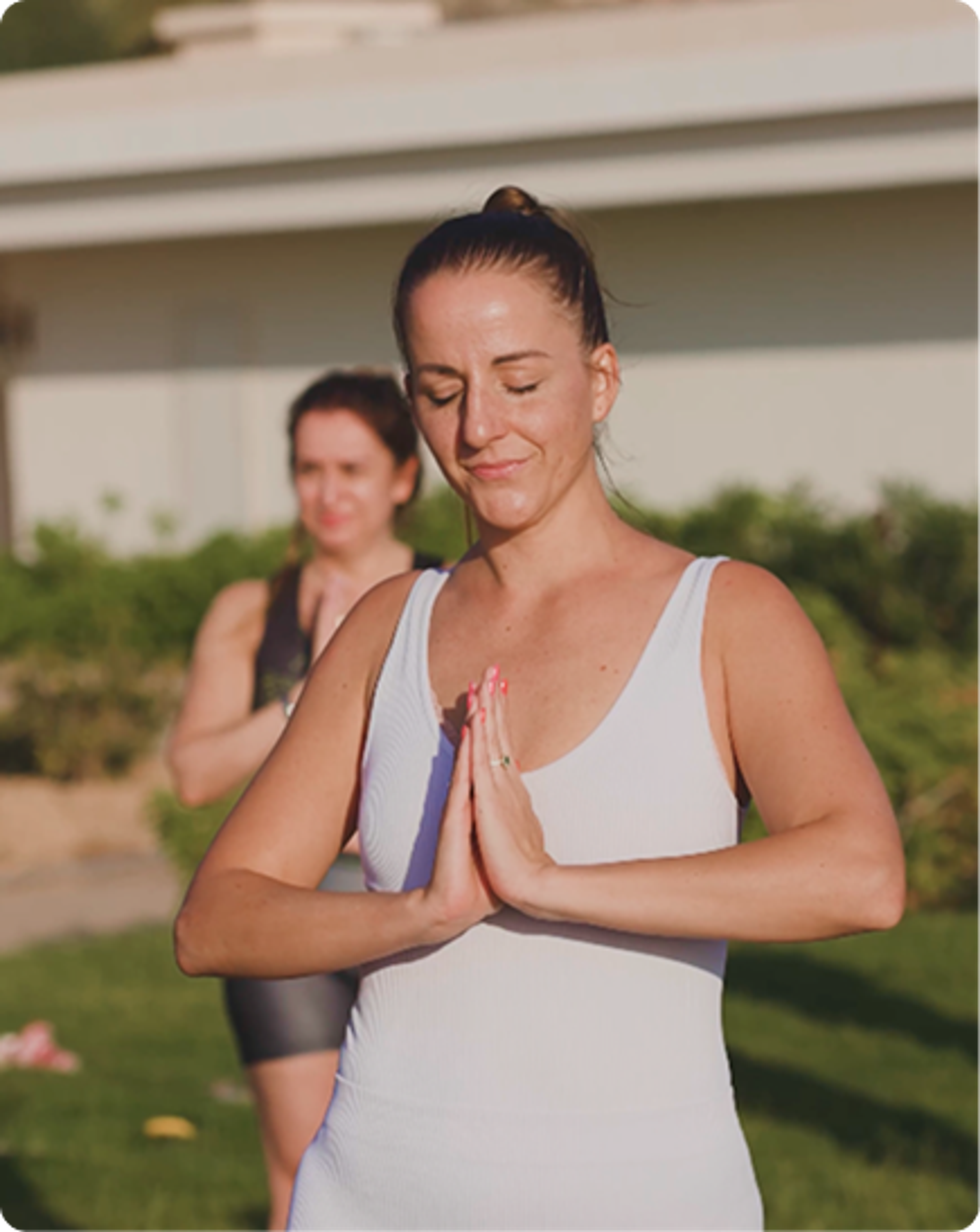 Guest practising outdoor yoga with eyes closed and palms together.