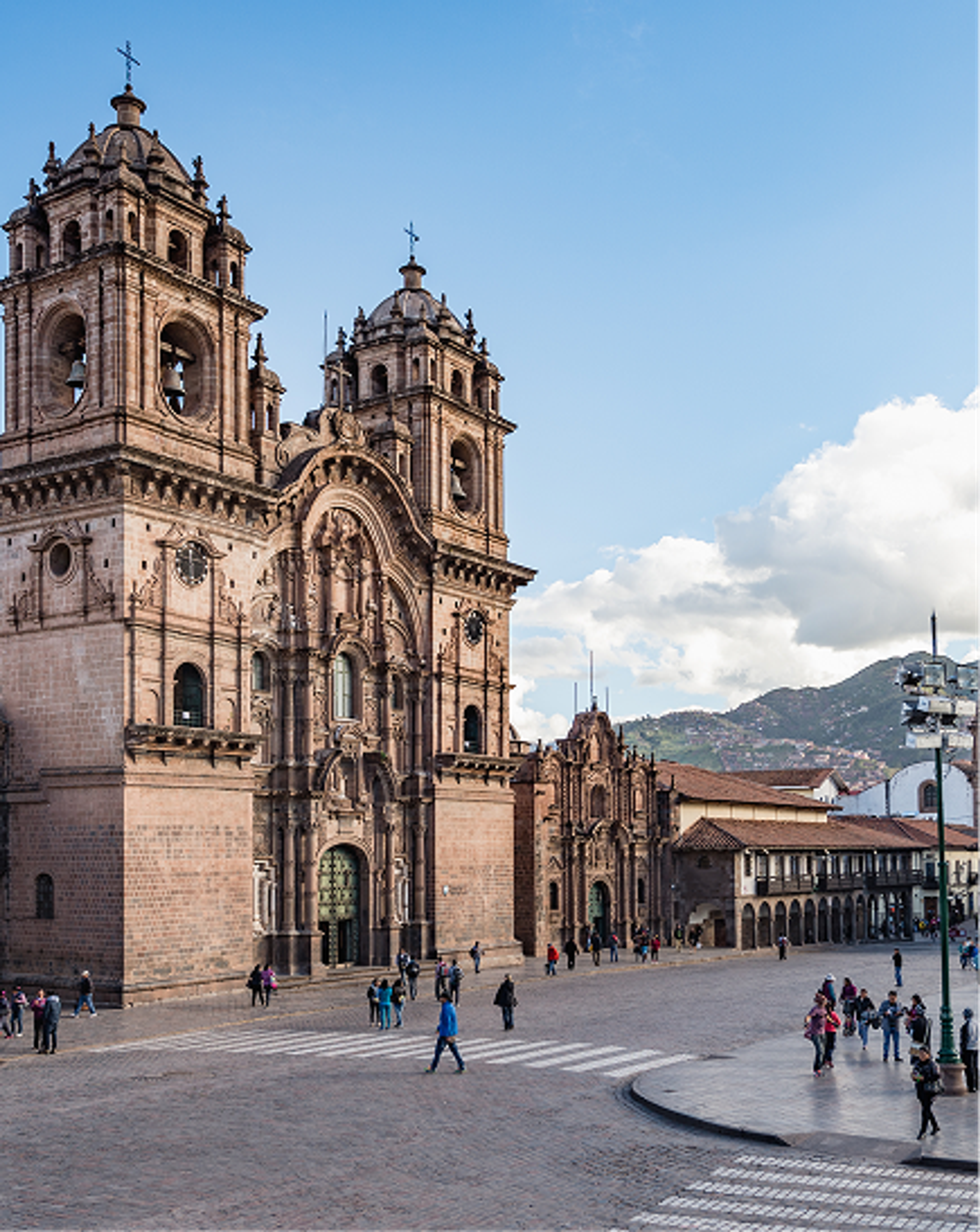 Historic stone church with twin bell towers overlooking a busy square.