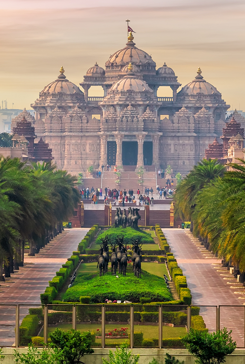 Ornate Indian temple overlooking landscaped gardens and a palm-lined walkway.