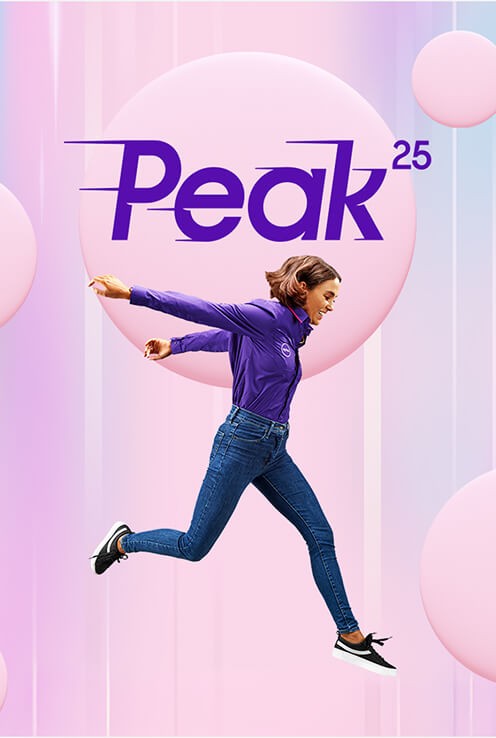 A woman in a purple long-sleeve shirt and jeans leaping in front of a Peak 25 logo and pink background spheres