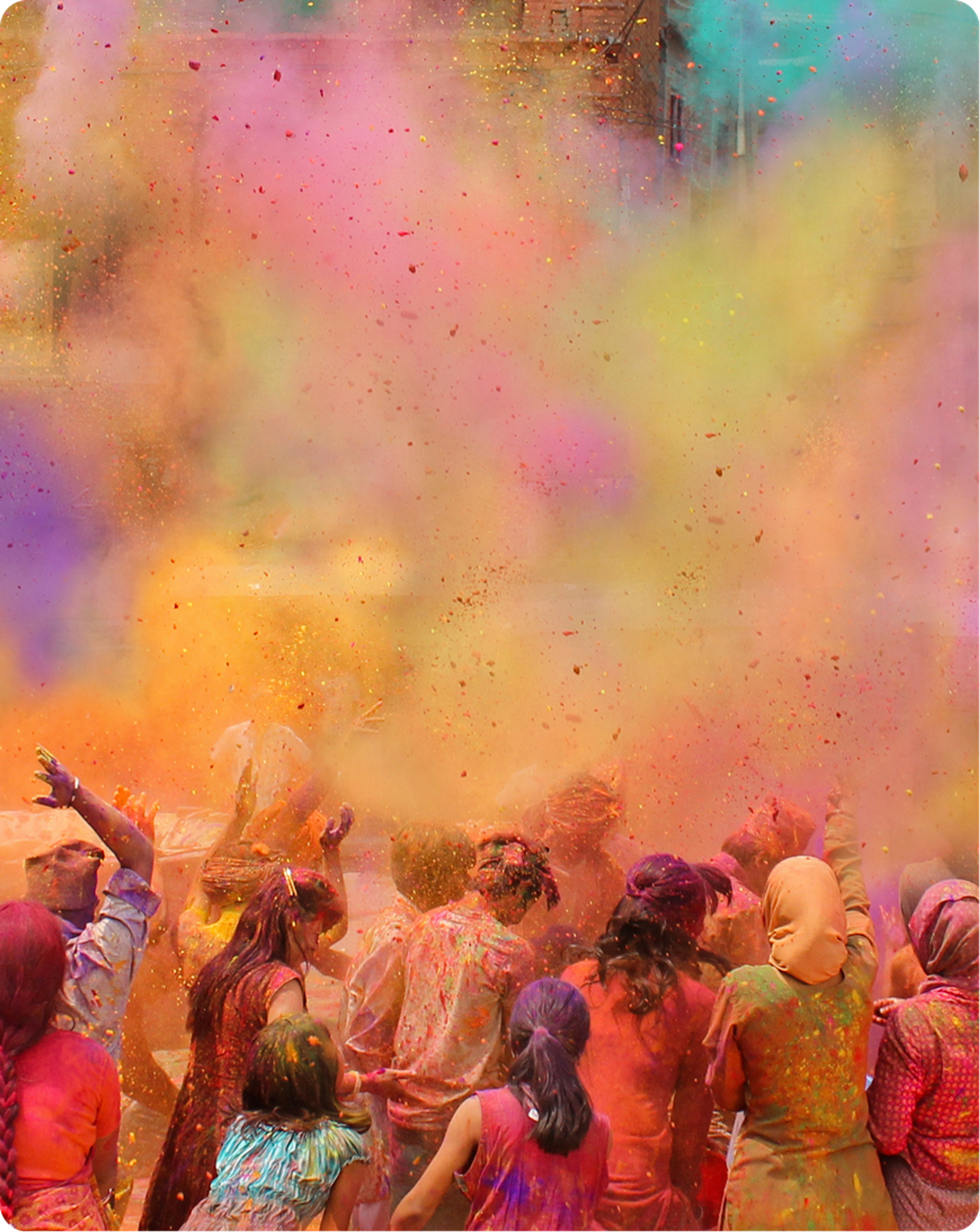 People celebrating beneath clouds of brightly coloured powder