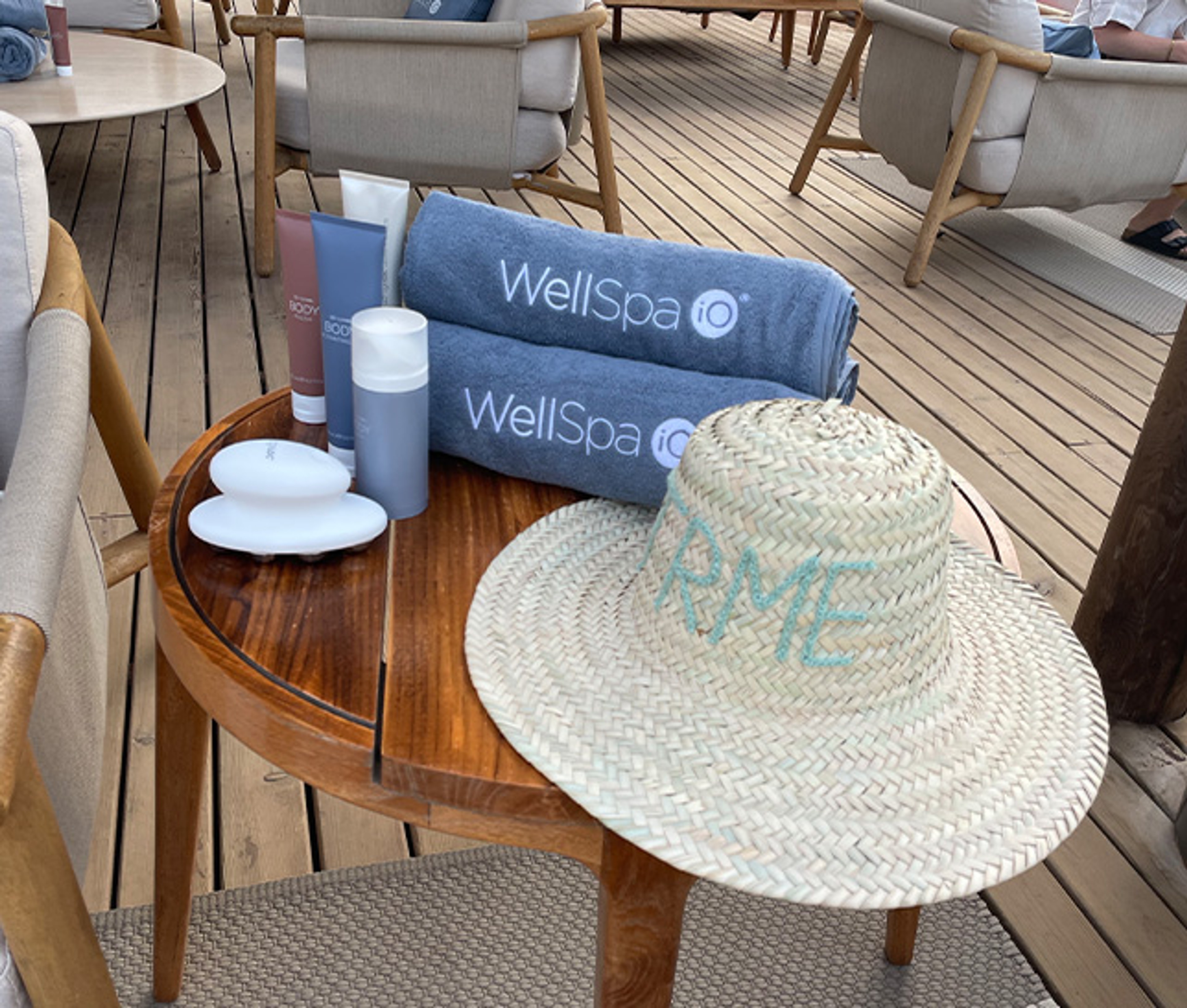Nu Skin WellSpa iO products and branded towels beside a personalised straw hat.