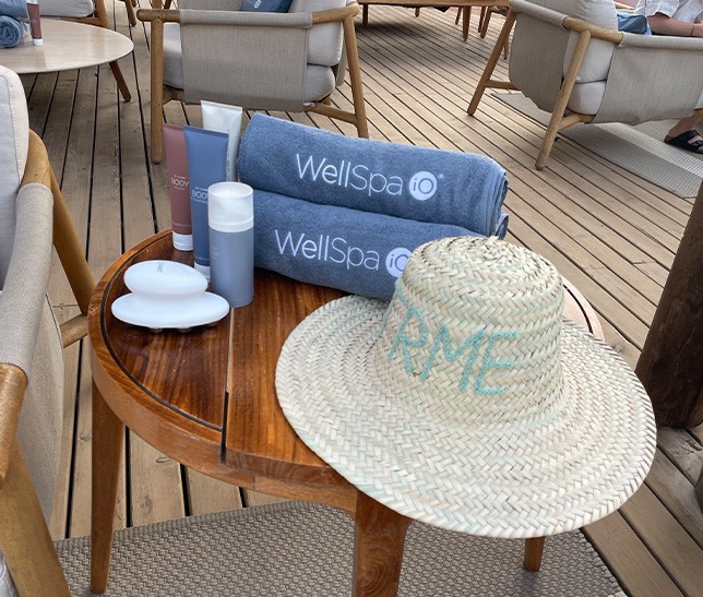 Nu Skin WellSpa iO products and branded towels beside a personalised straw hat.