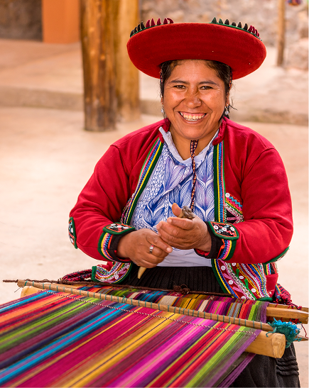 Smiling artisan in traditional dress weaving a brightly coloured textile.