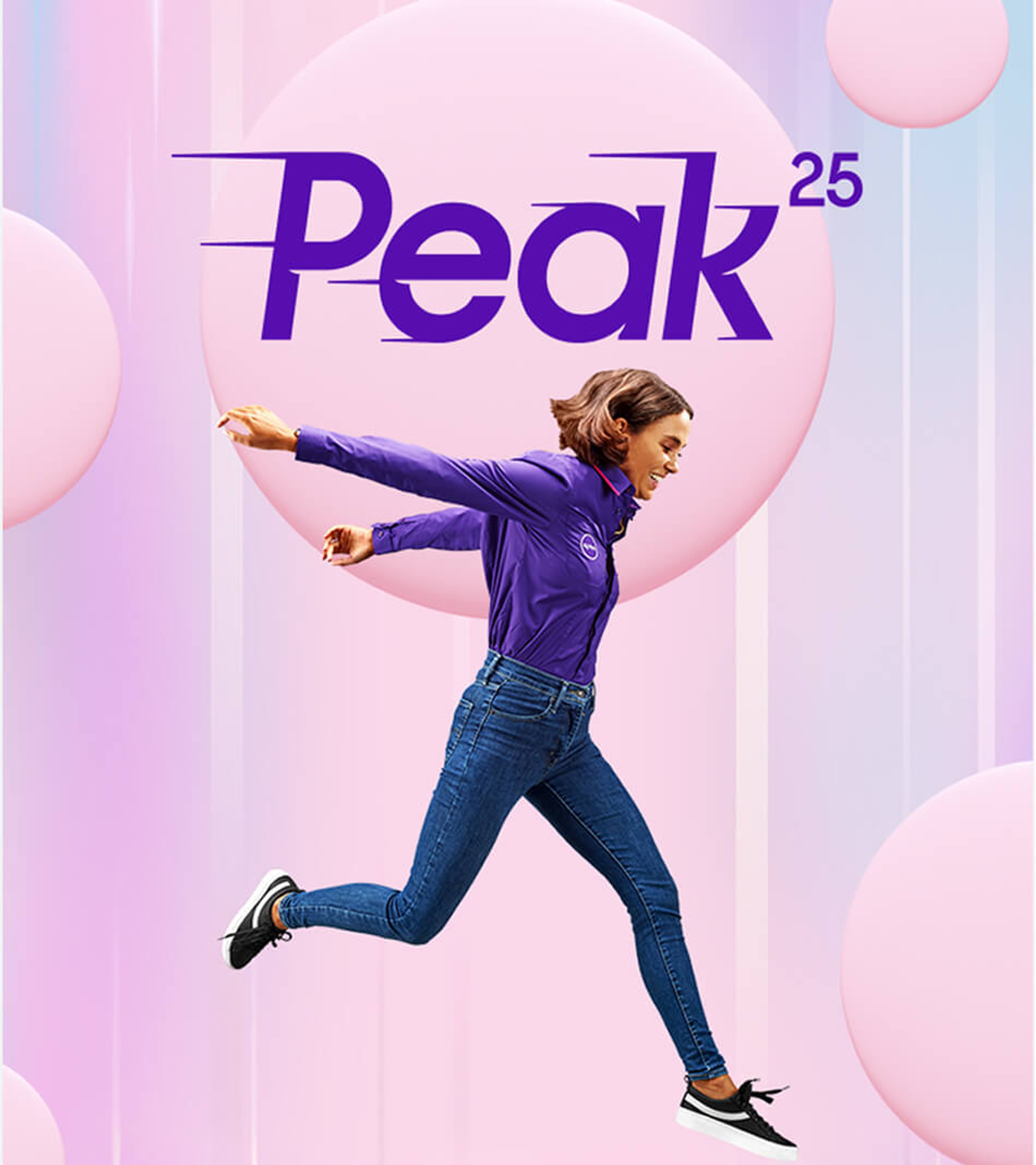 A woman in a purple long-sleeve shirt and jeans leaping happily in front of a Peak 25 logo and pink background spheres