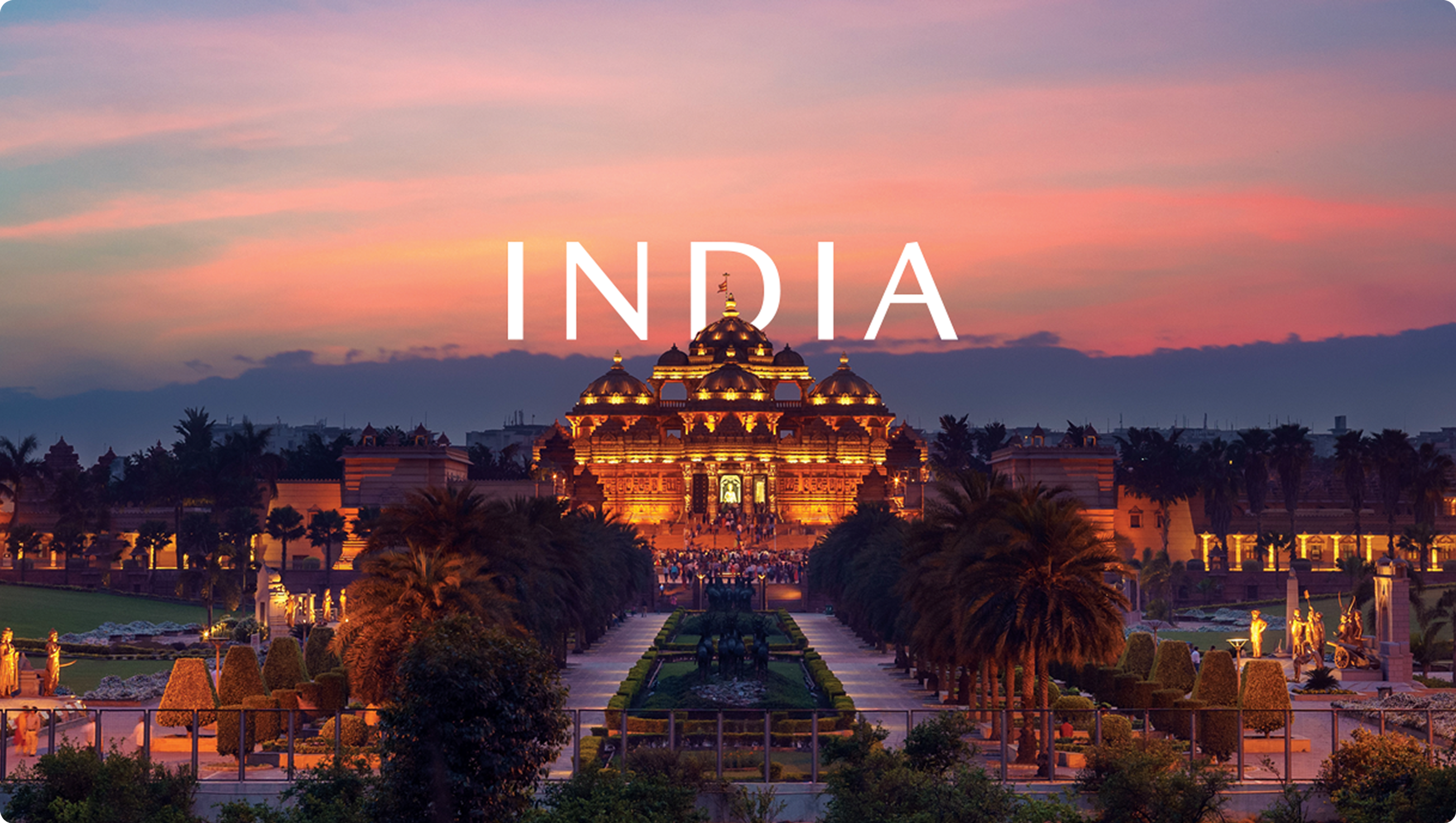 Illuminated temple and landscaped gardens at sunset, with ‘India’ in white lettering.