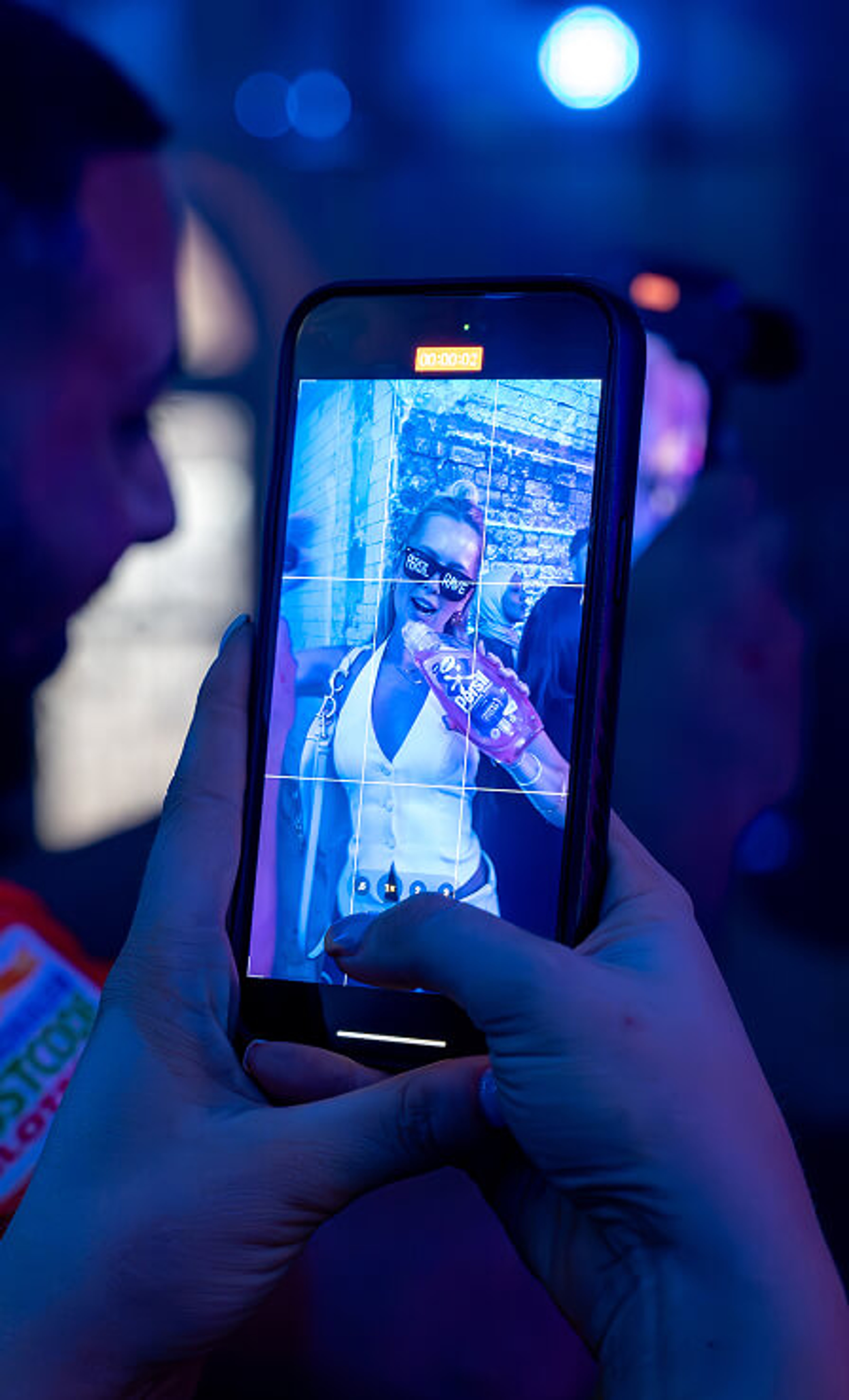 Close-up of a smartphone screen recording a woman holding a Persil bottle under blue event lighting