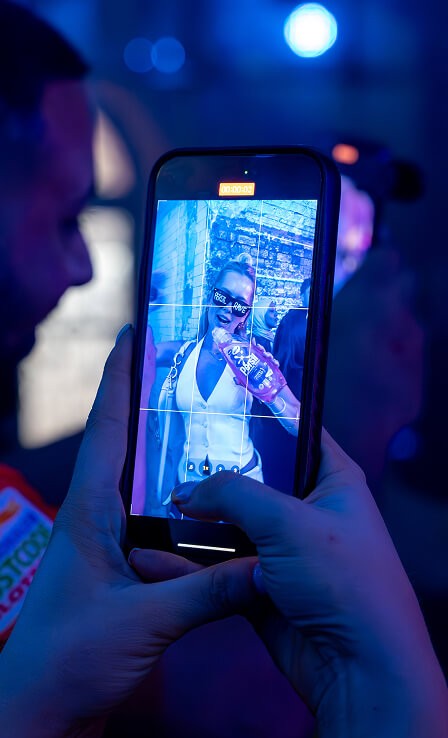 Close-up of a smartphone screen recording a woman holding a Persil bottle under blue event lighting